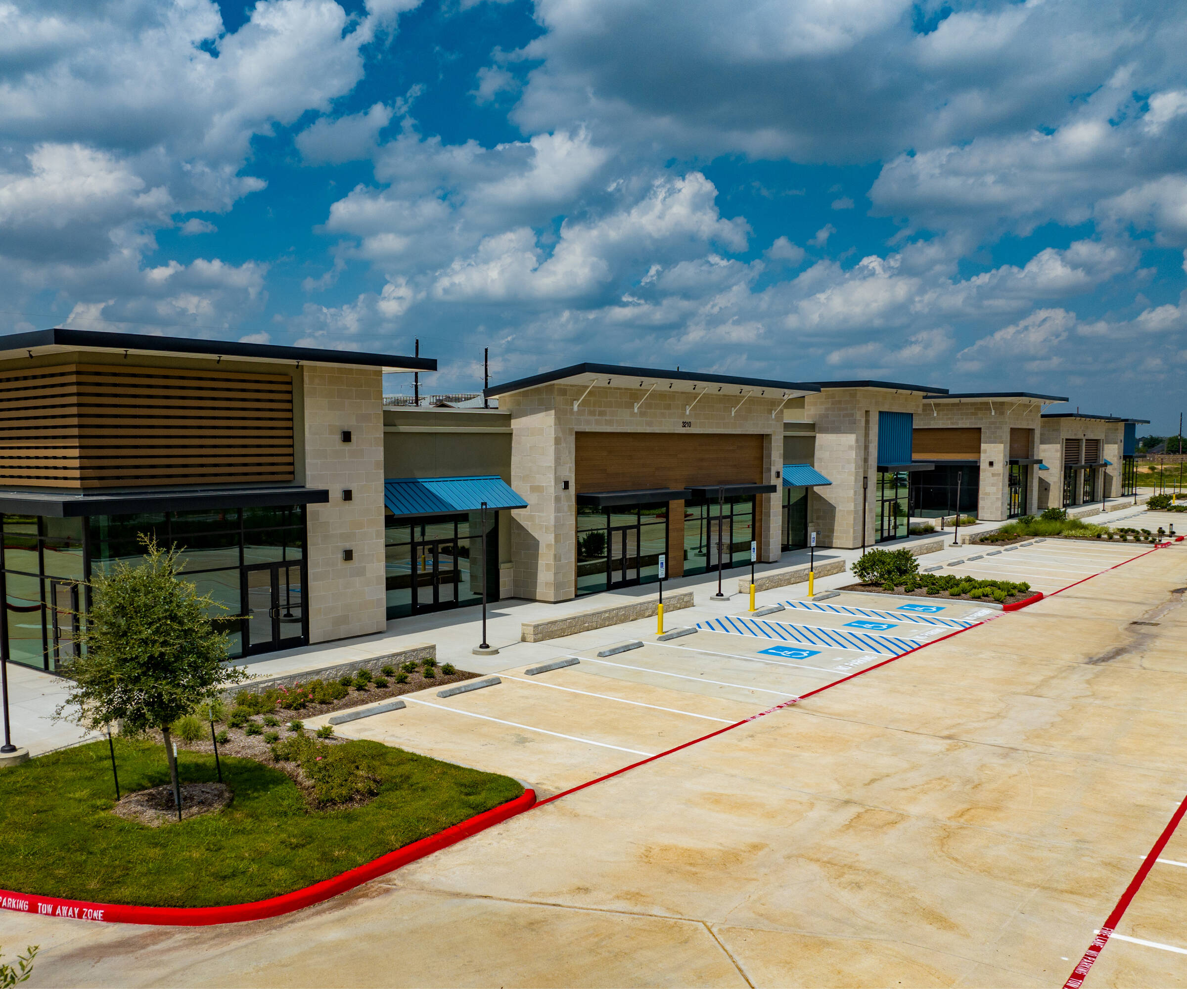 Aerial view of a modern retail strip center with ample parking and multiple tenant spaces in Katy, TX.