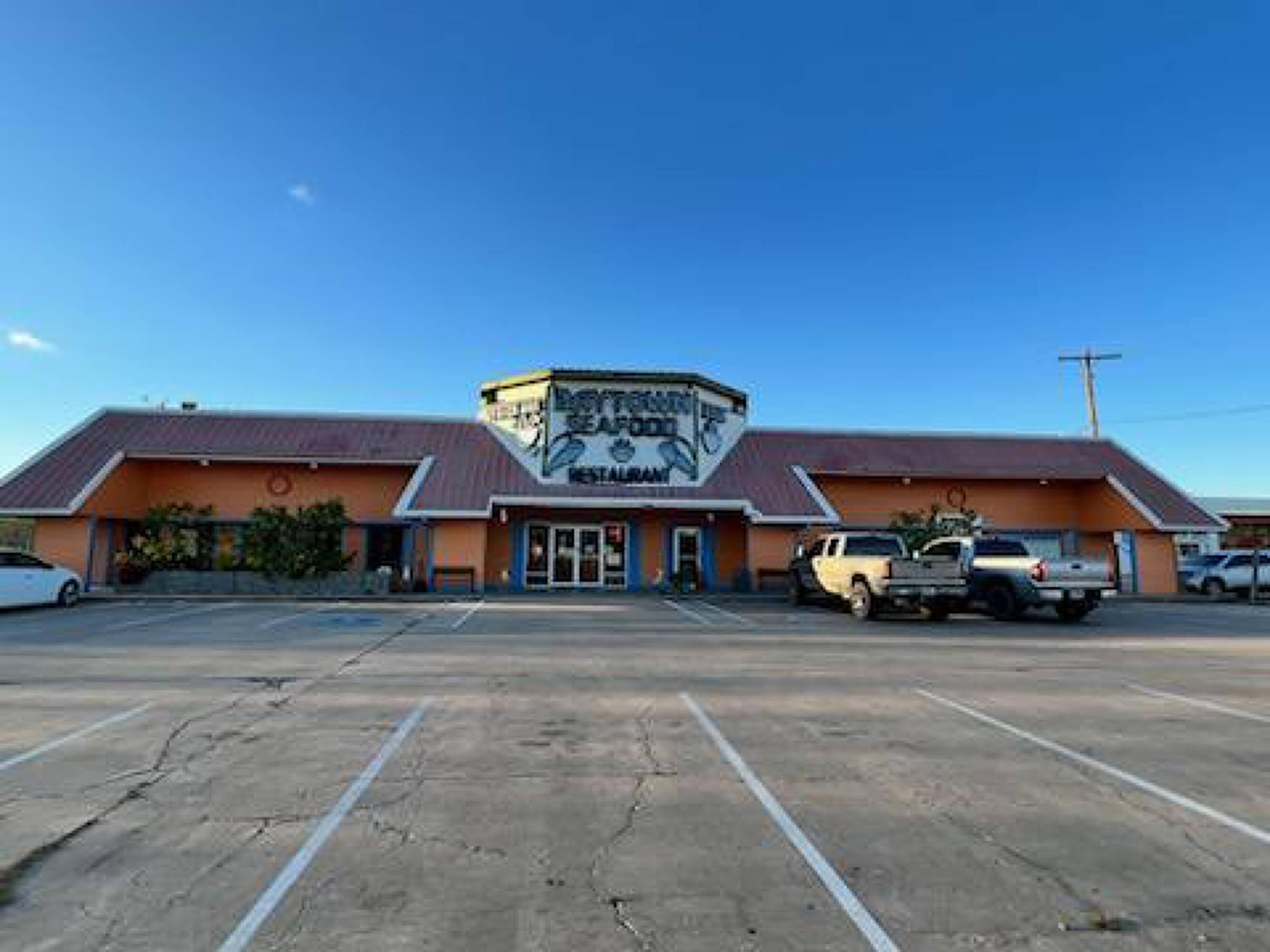 Front view of a single-story commercial building with a restaurant sign, large windows, and ample parking in West Columbia, TX.