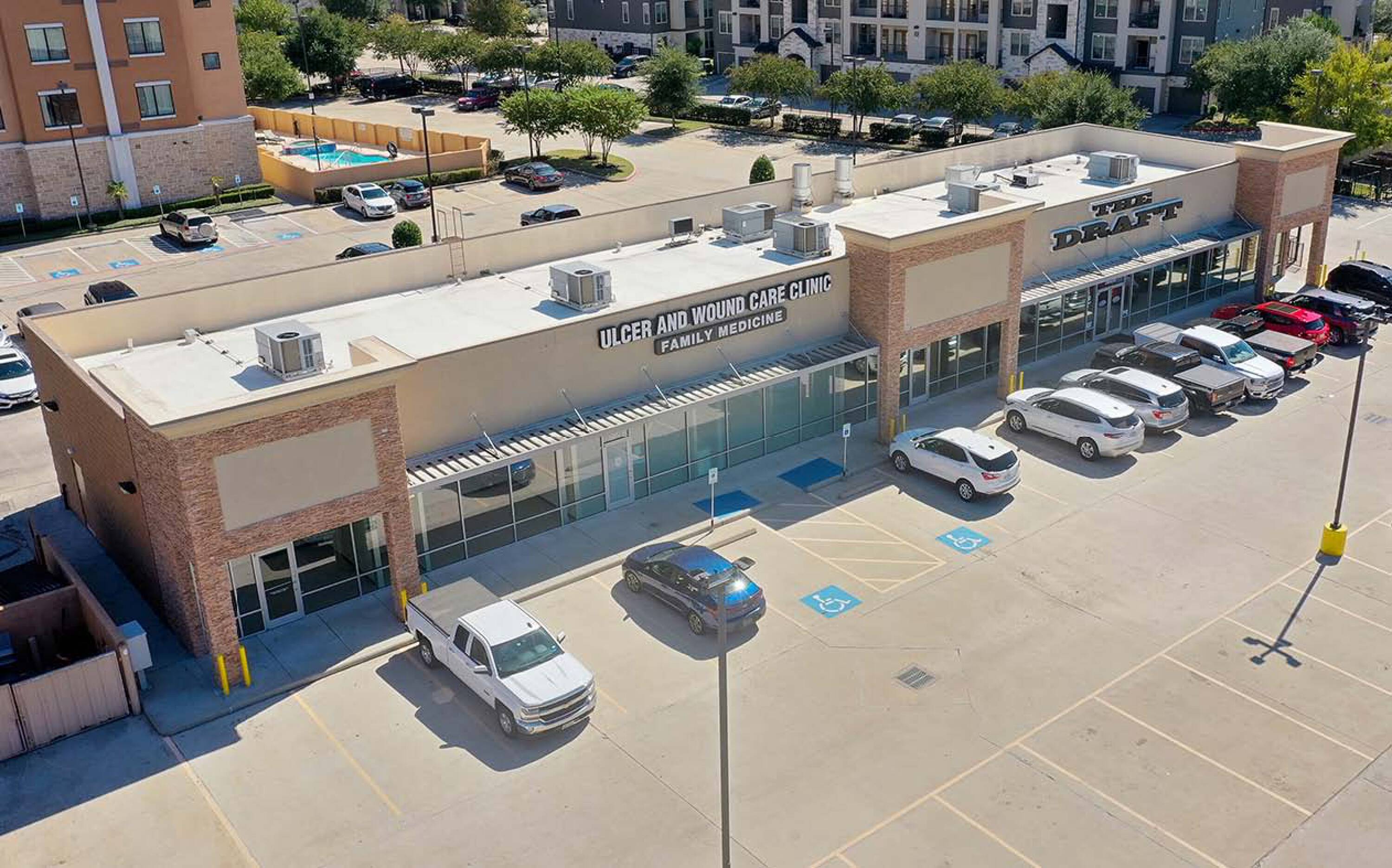 Aerial view of a single-story retail strip with multiple tenant spaces and ample parking in Kingwood, TX.