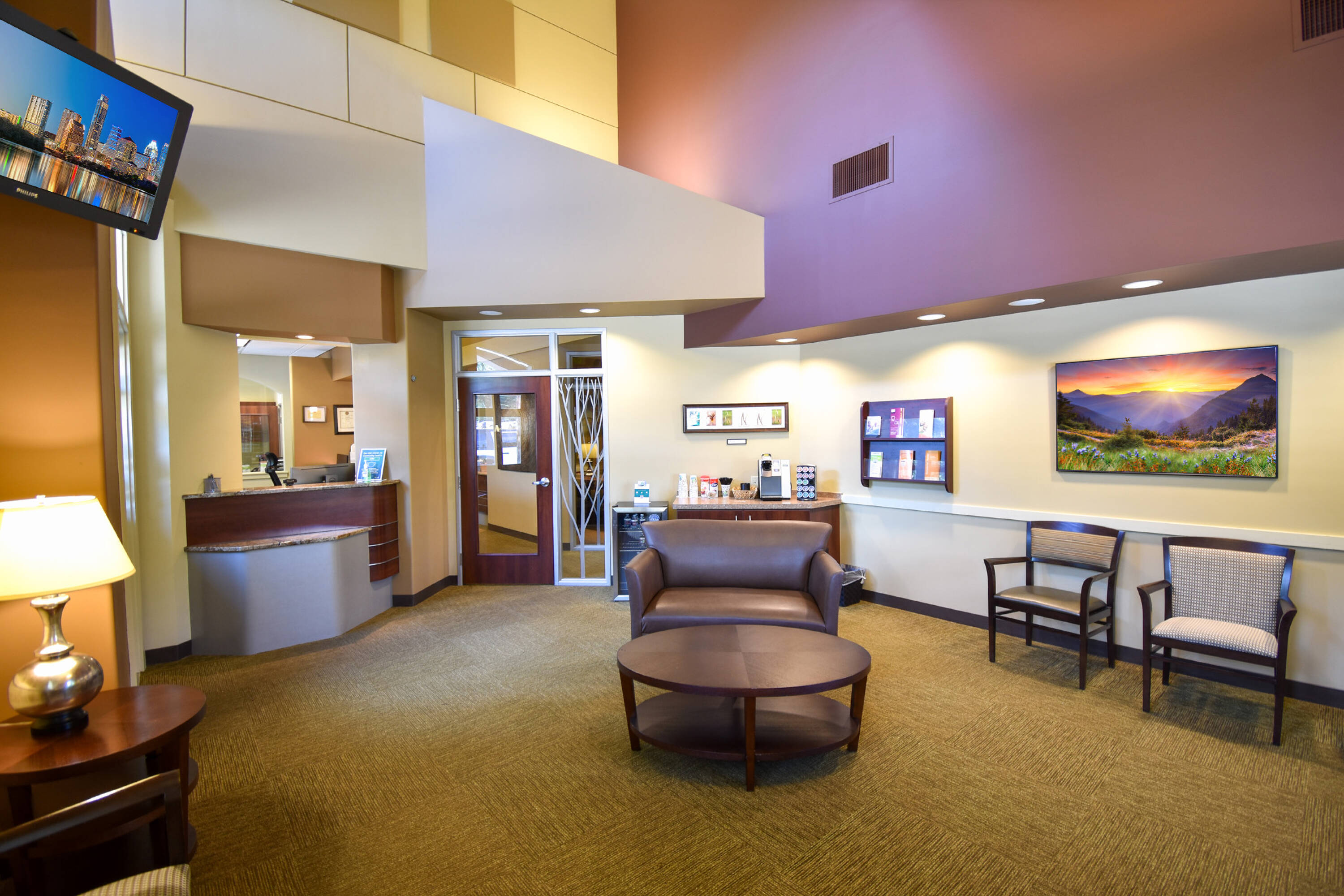 Interior view of a modern dental office with reception area, seating, and ample natural light.
