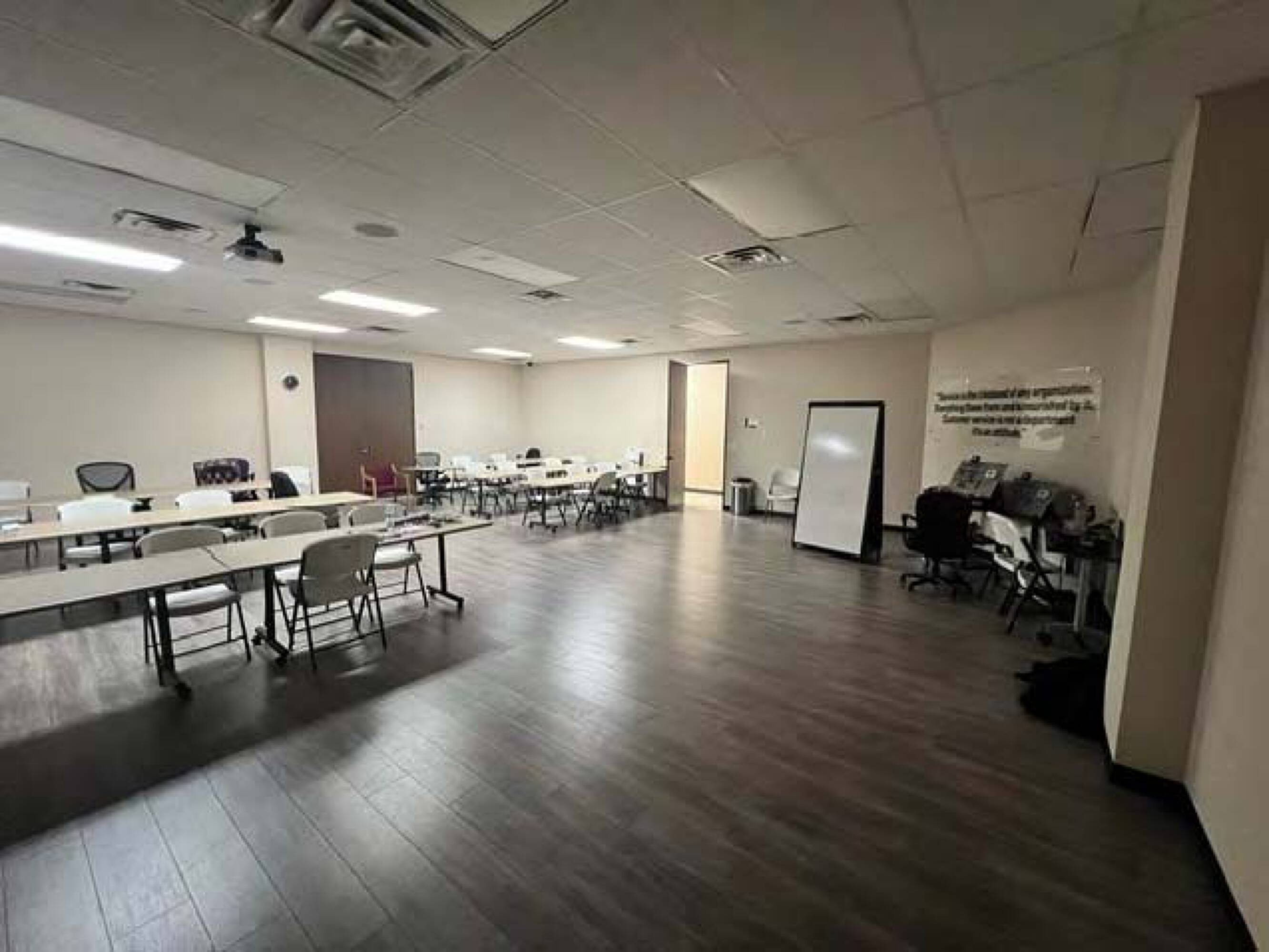 Spacious training room with tables, chairs, whiteboard, and motivational quote on the wall.