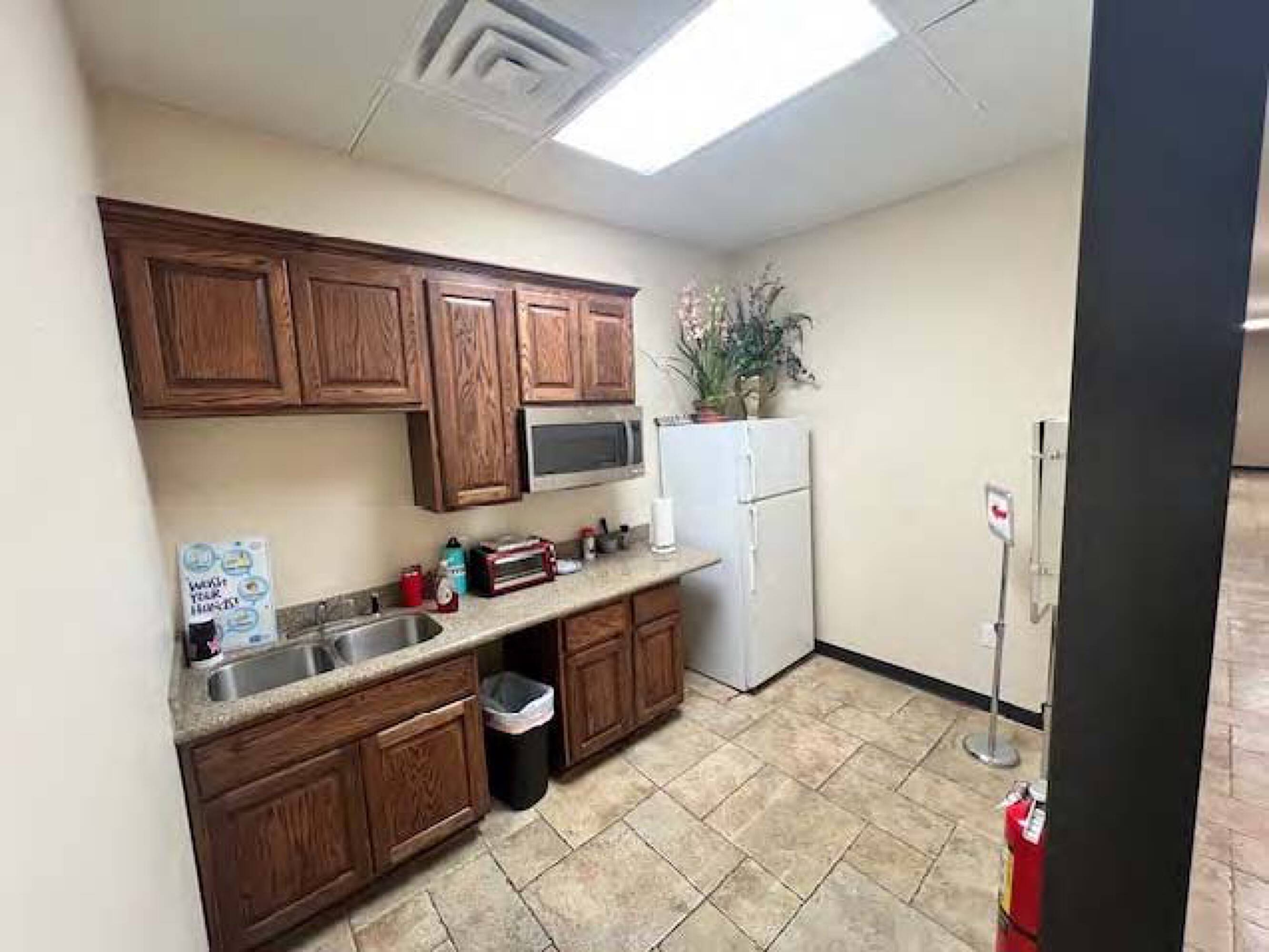 Kitchen area with wood cabinetry, stainless steel appliances, and tile flooring in Four Seasons Business Park.