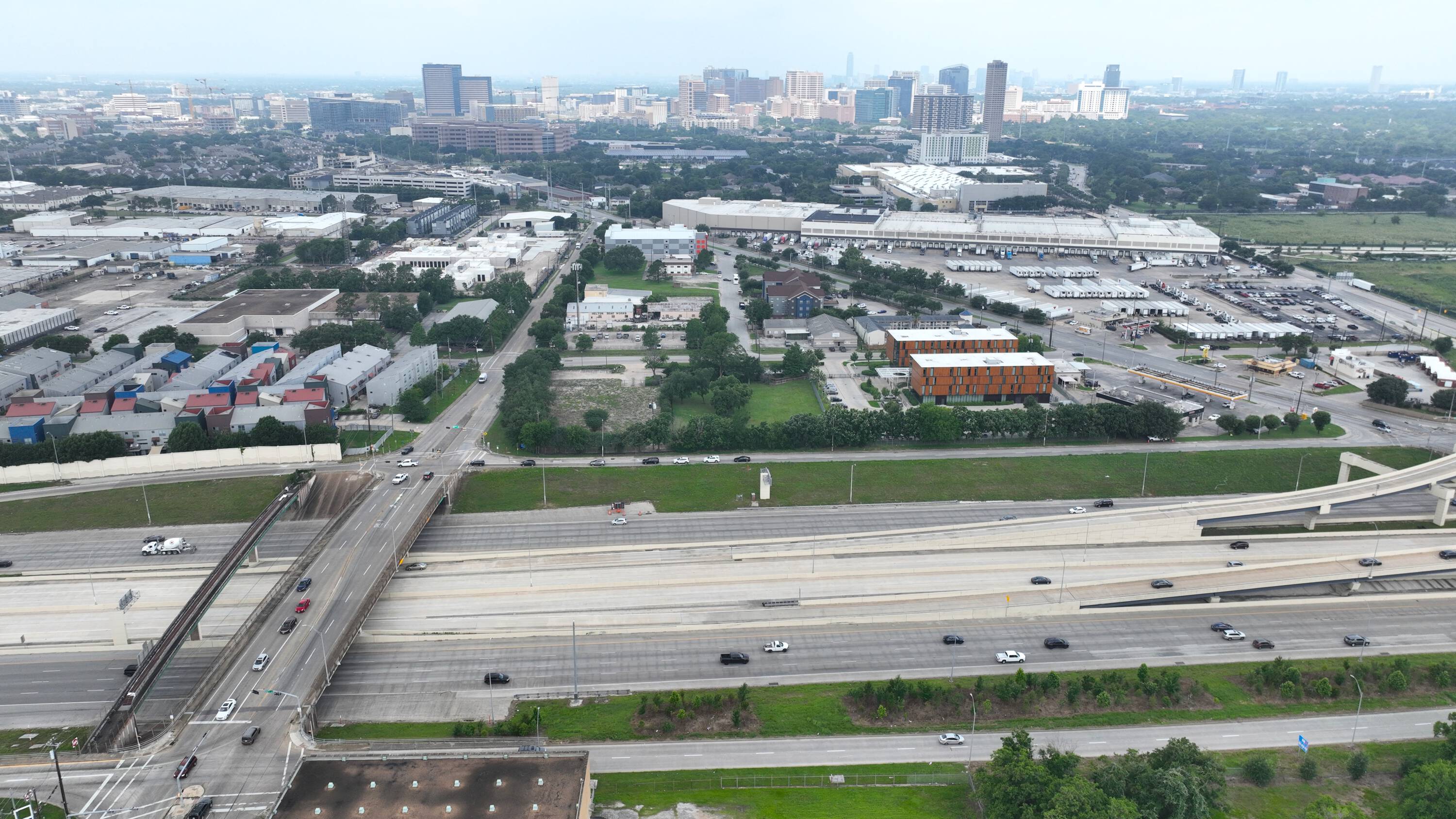Aerial view of 6897 Ardmore St, Houston, TX, showing a large vacant land parcel near industrial and commercial buildings with highway access.