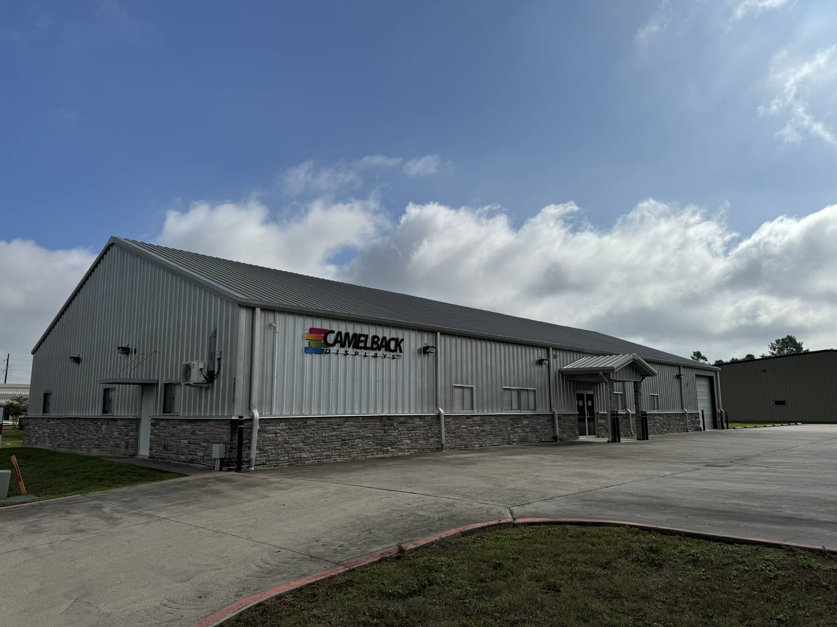 Exterior view of a single-story industrial/office building with ample parking and loading areas in Spring, TX.