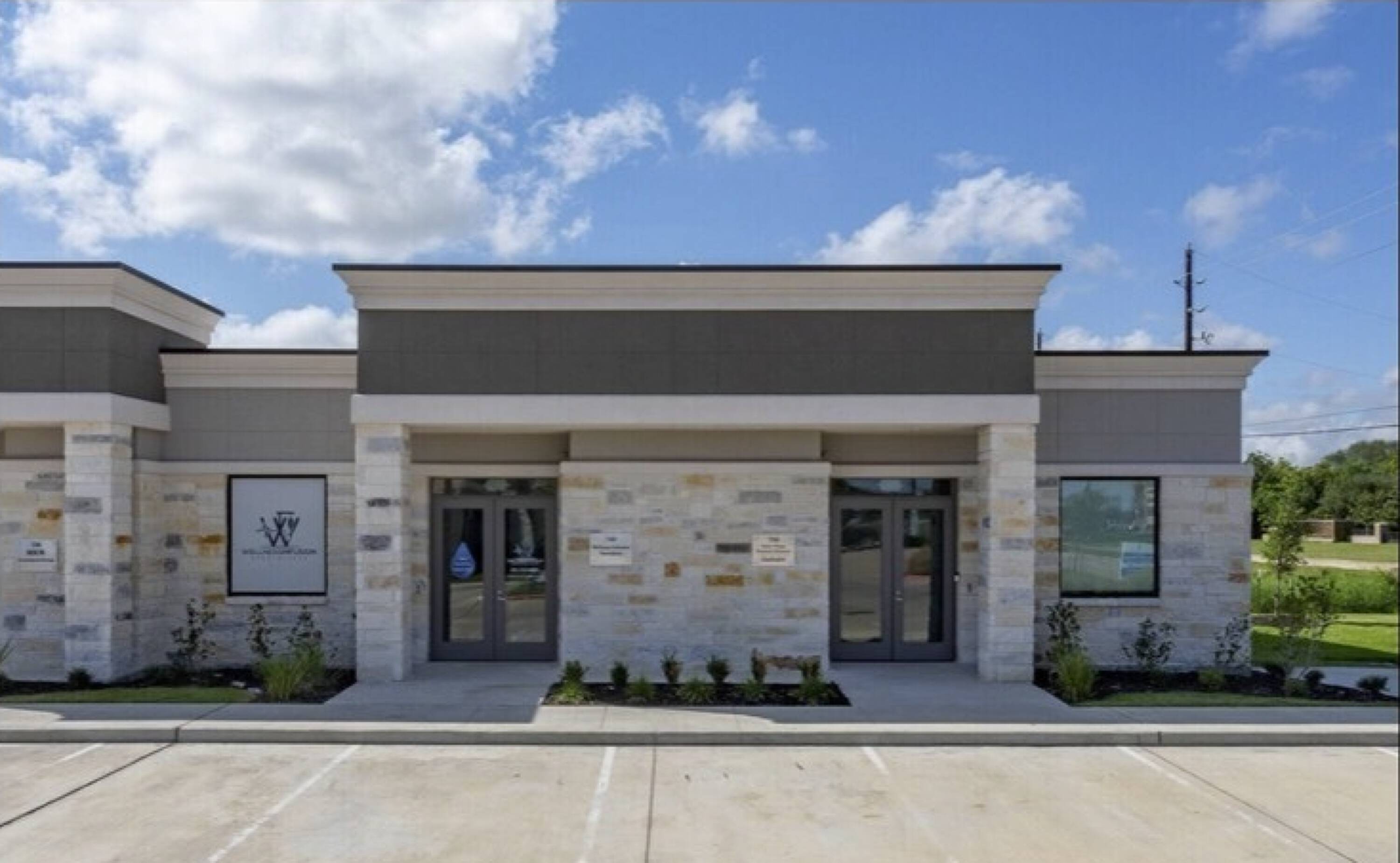 Exterior view of Woodforest Medical Center - Building 4 with stone and stucco facade, large windows, and surface parking.