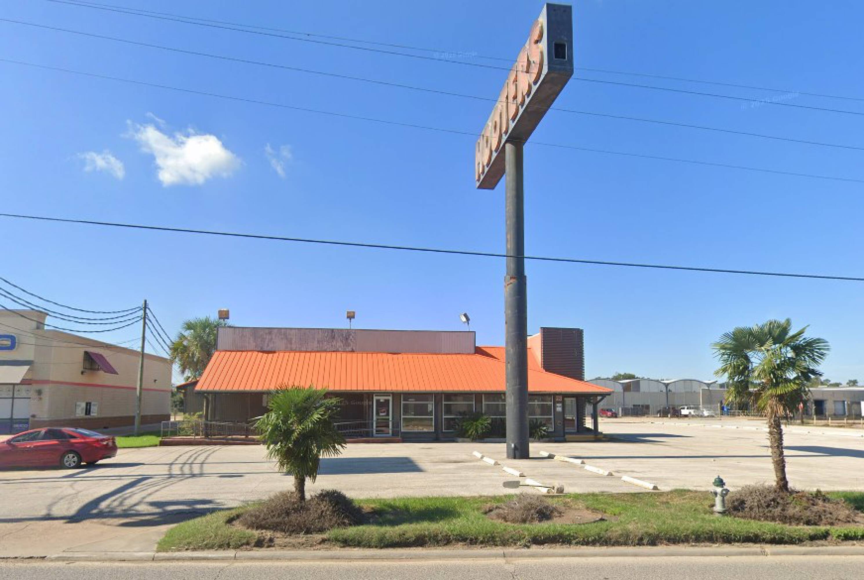 Vacant restaurant building with large windows, ample parking, and prominent signage in Beaumont, TX.