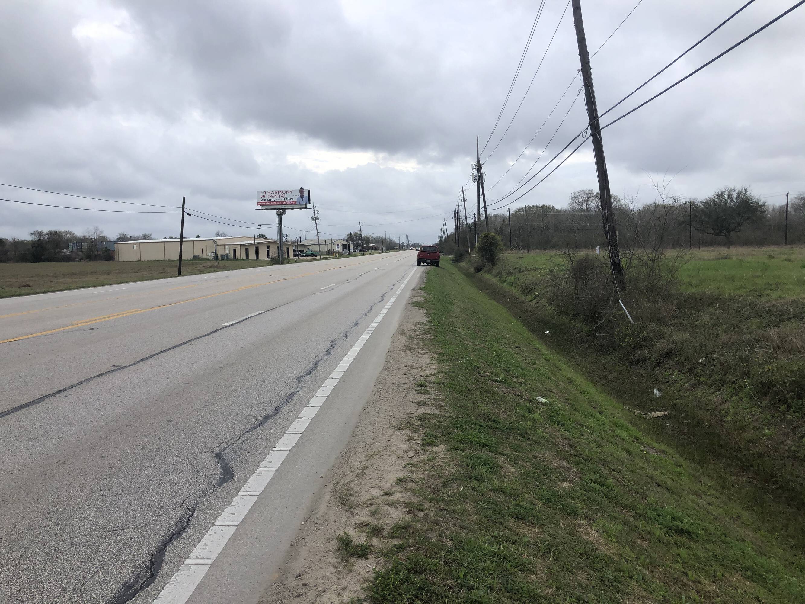 Image of a vacant land parcel at 3200 Main St, Pearland, TX with direct road access and commercial neighbors.