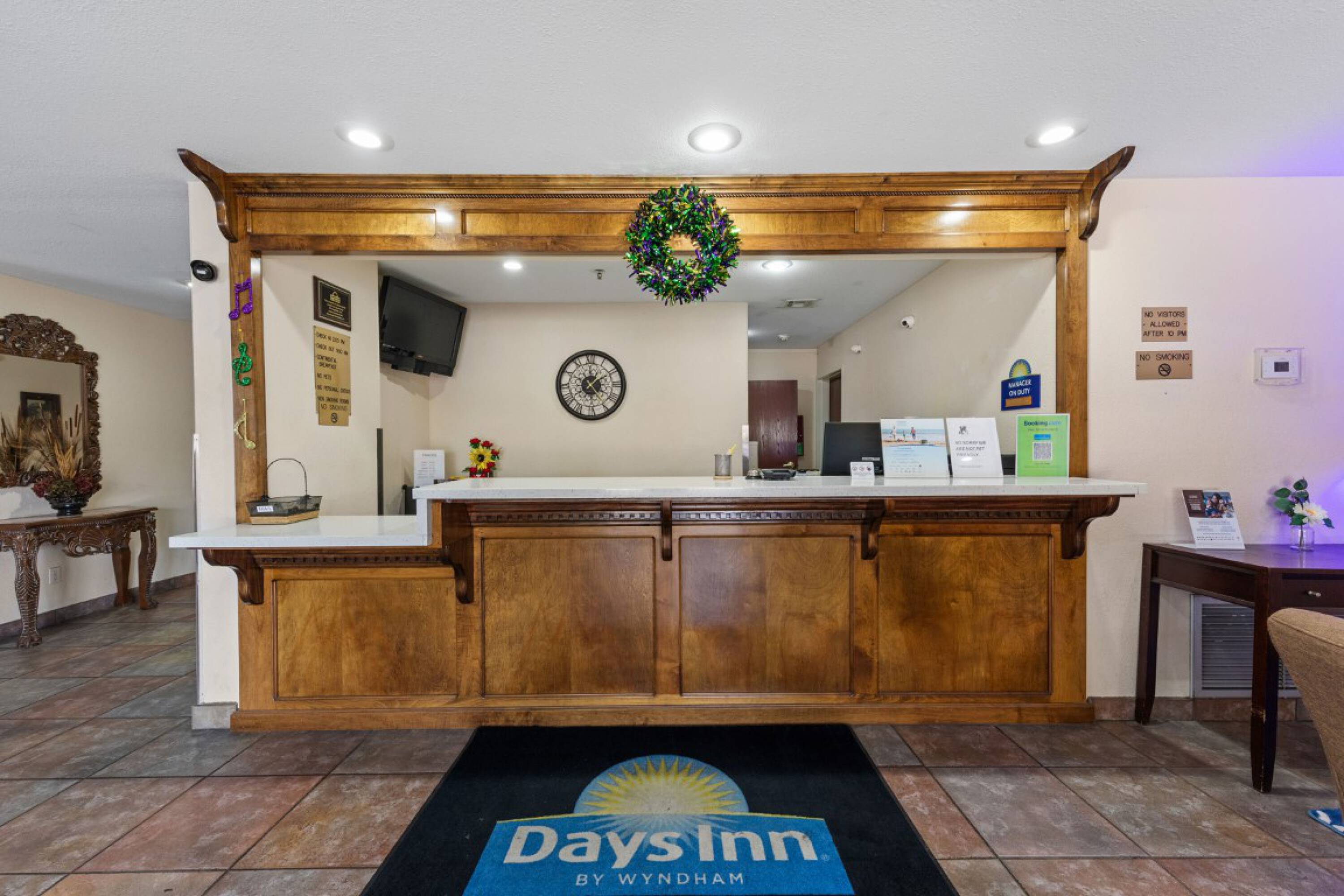 Reception area of Days Inn & Suites by Wyndham Eunice with a wooden desk, natural light, and decorative elements.