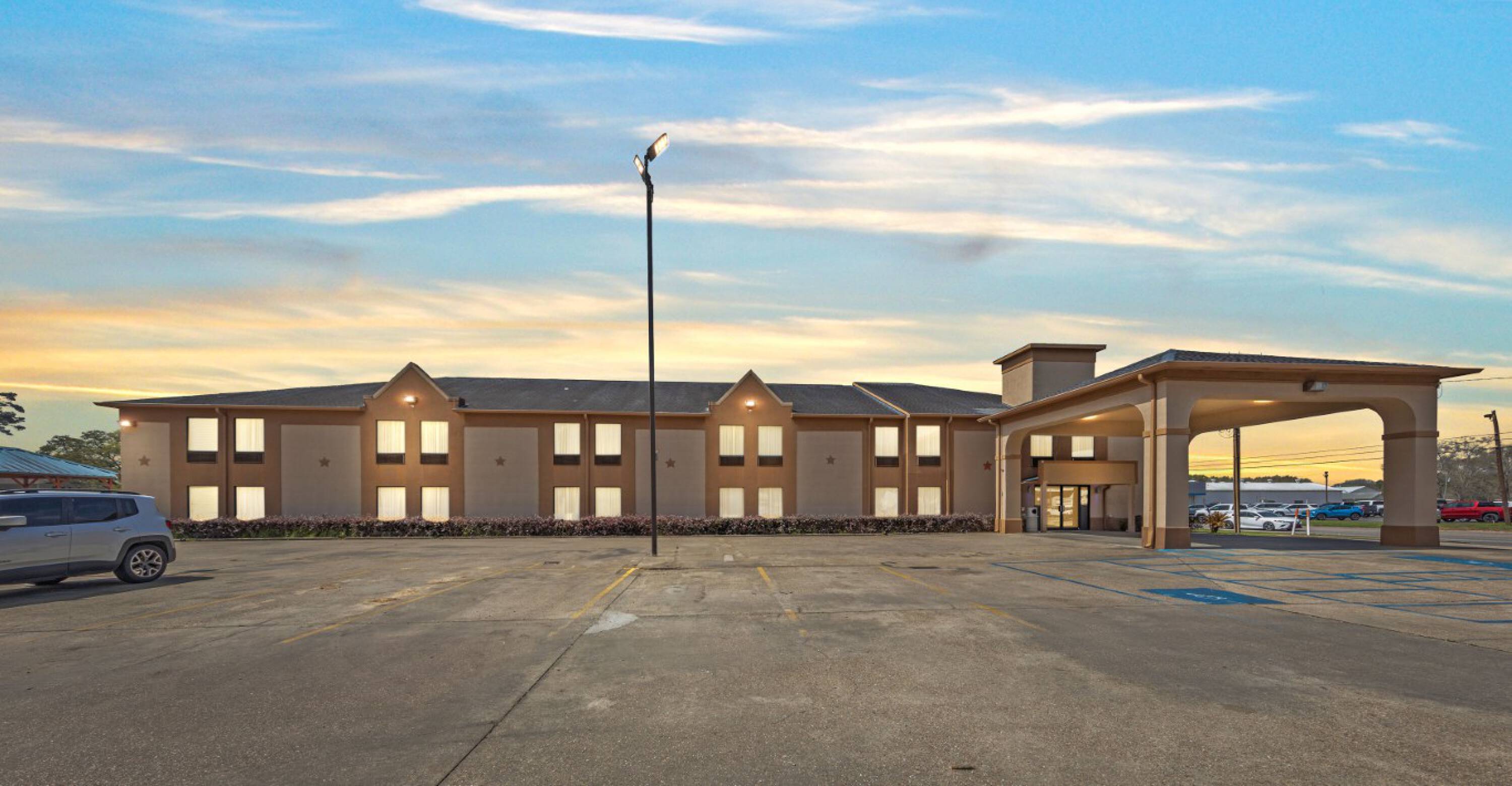 Front view of the Days Inn & Suites by Wyndham Eunice with a spacious parking lot and covered entrance.