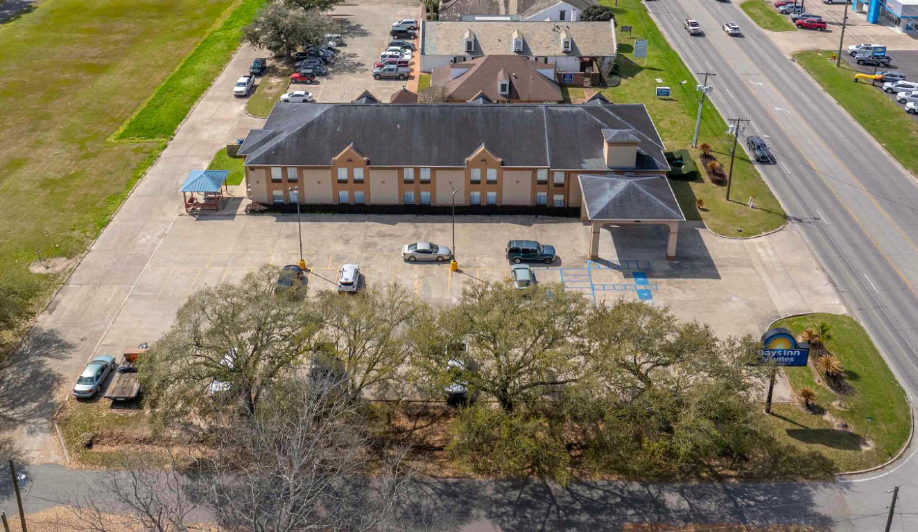 Aerial view of Days Inn & Suites by Wyndham Eunice with parking lot and adjacent buildings.