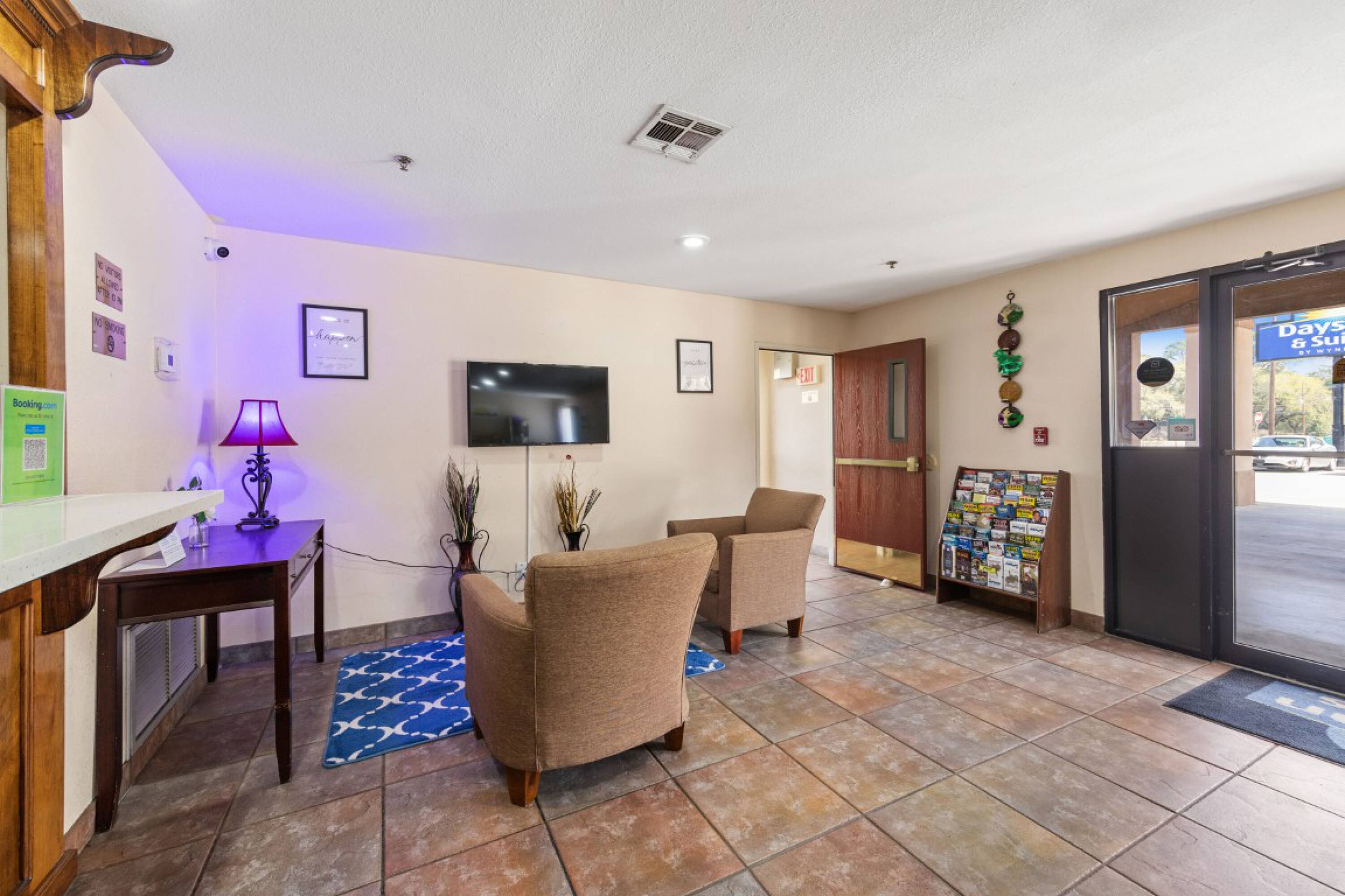 Reception area of Days Inn & Suites by Wyndham Eunice with seating, TV, and main entrance.