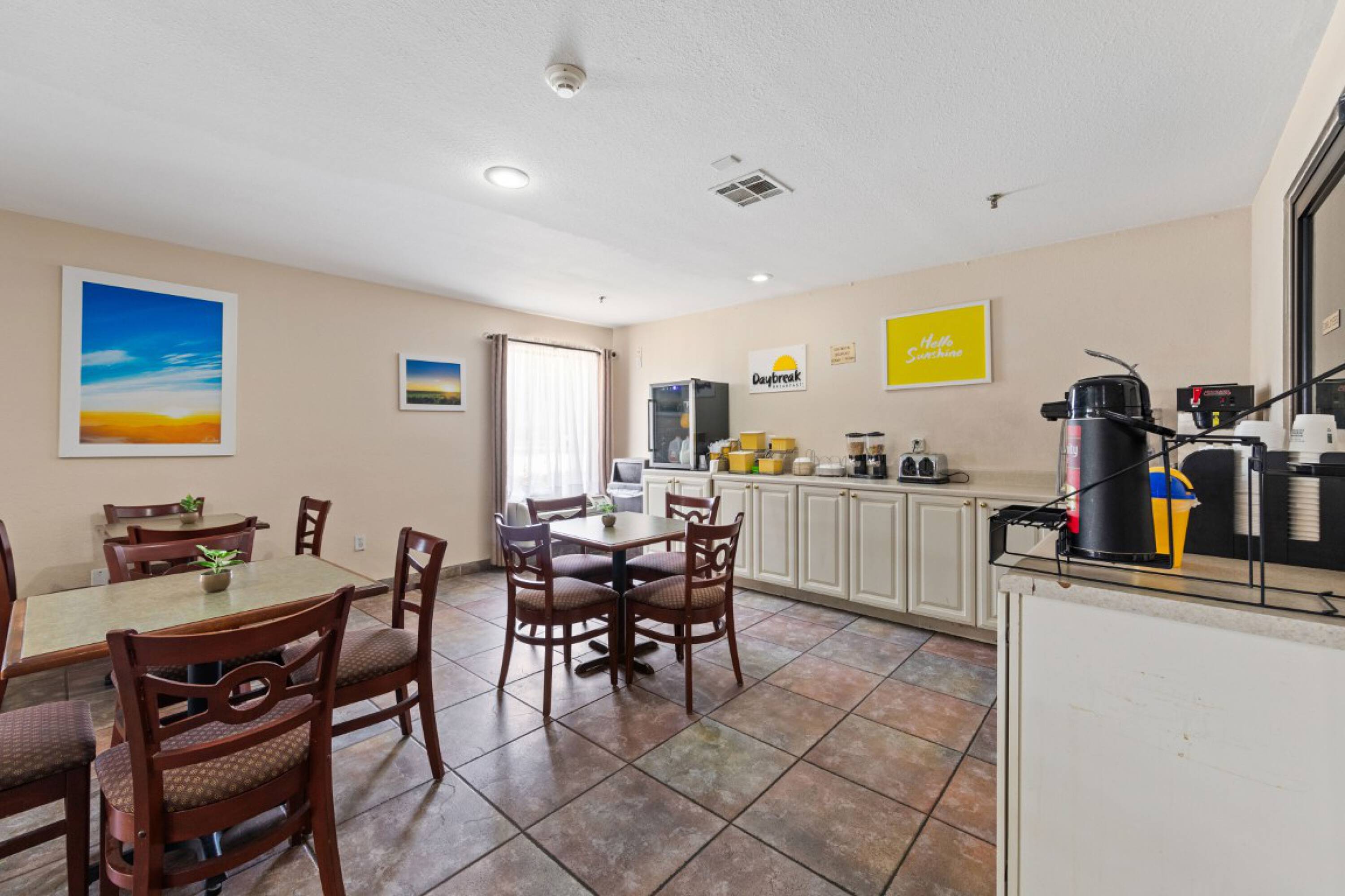 Dining area in the Days Inn & Suites by Wyndham Eunice with tables, chairs, and a self-serve coffee station.