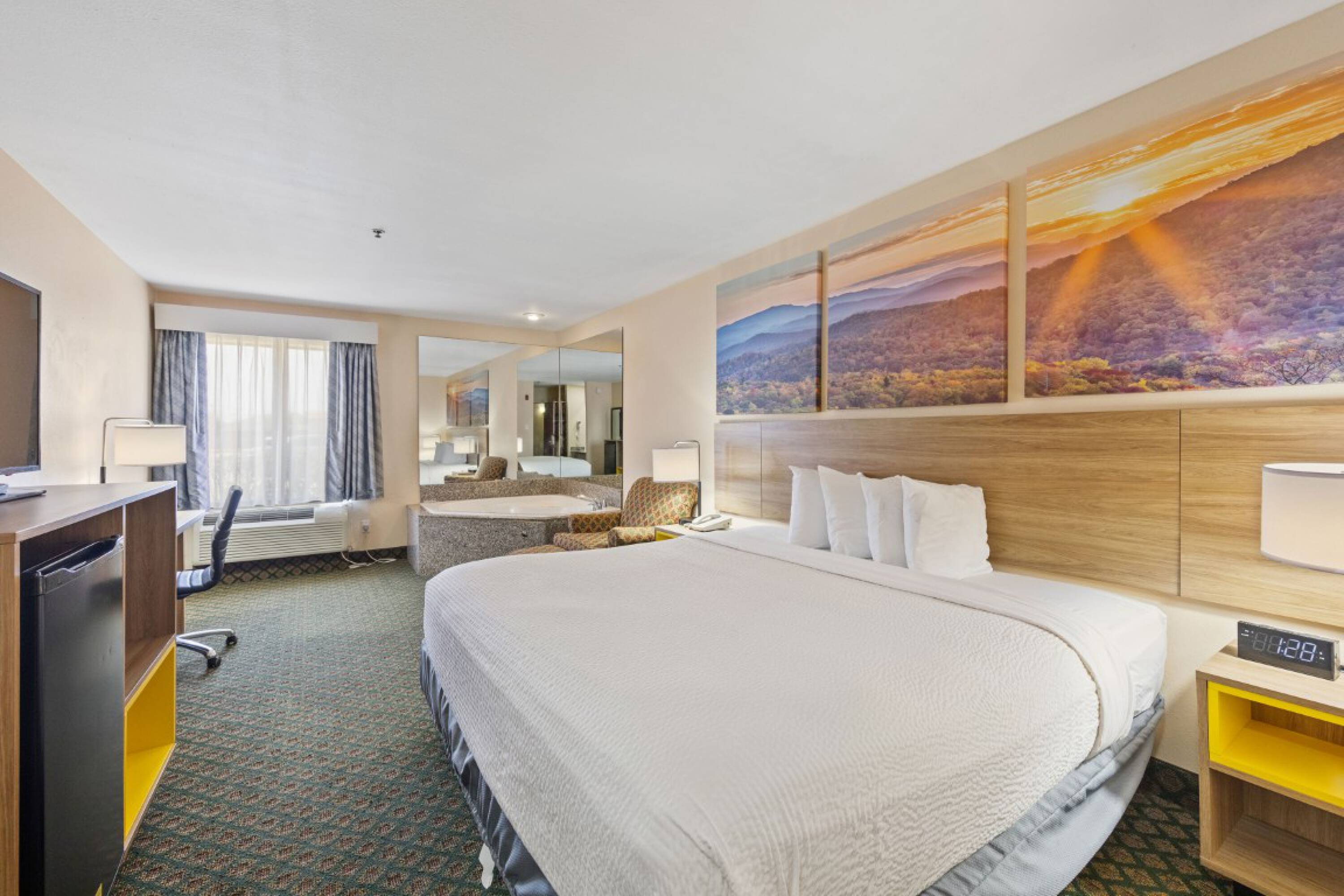 Modern hotel room with large windows, scenic murals, and comfortable bedding at Days Inn & Suites by Wyndham Eunice.