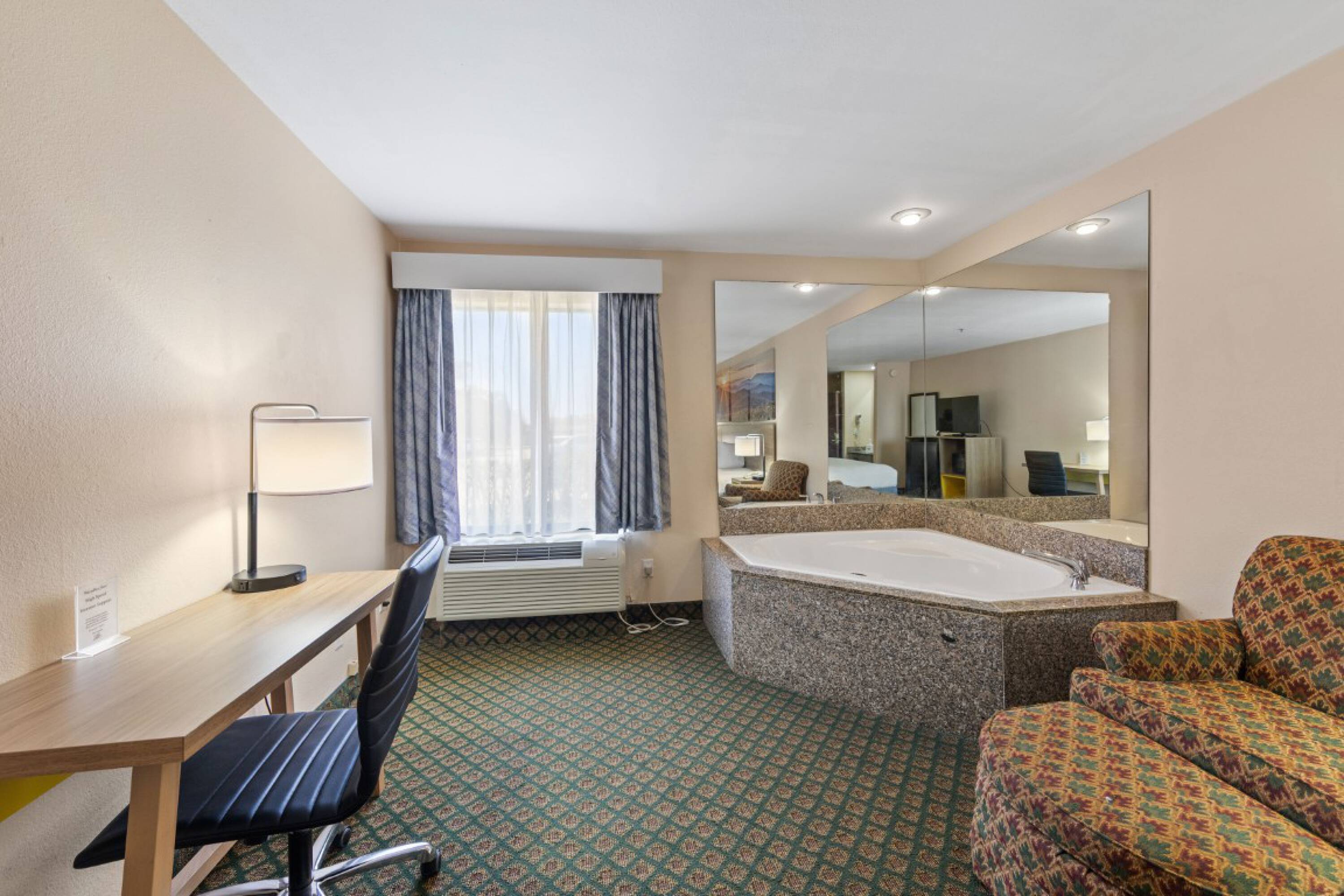 Hotel room at Days Inn & Suites by Wyndham Eunice featuring a work desk, seating, and an in-room jacuzzi.