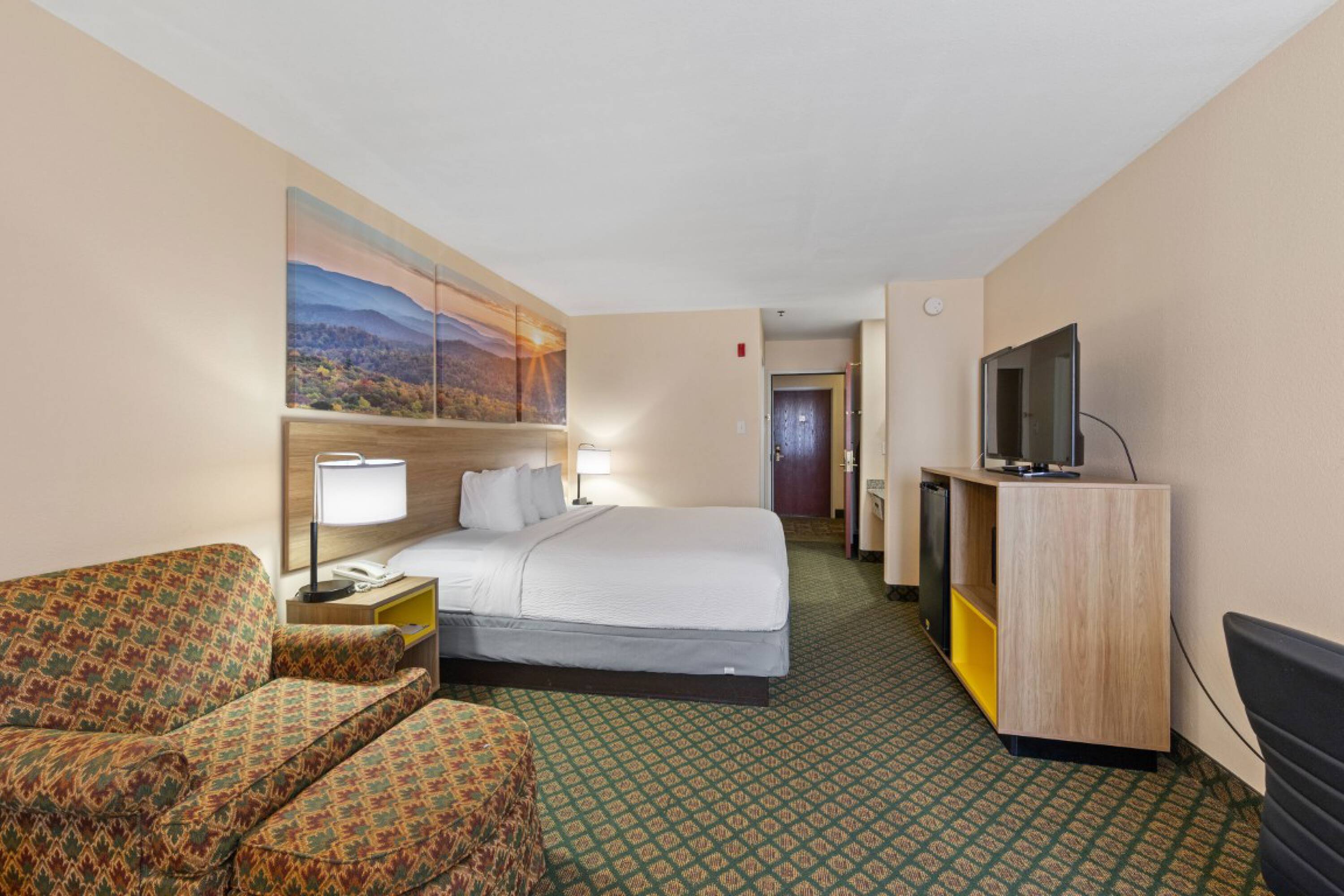 Guest room at Days Inn & Suites by Wyndham Eunice featuring a king-size bed, armchair, and flat-screen TV.