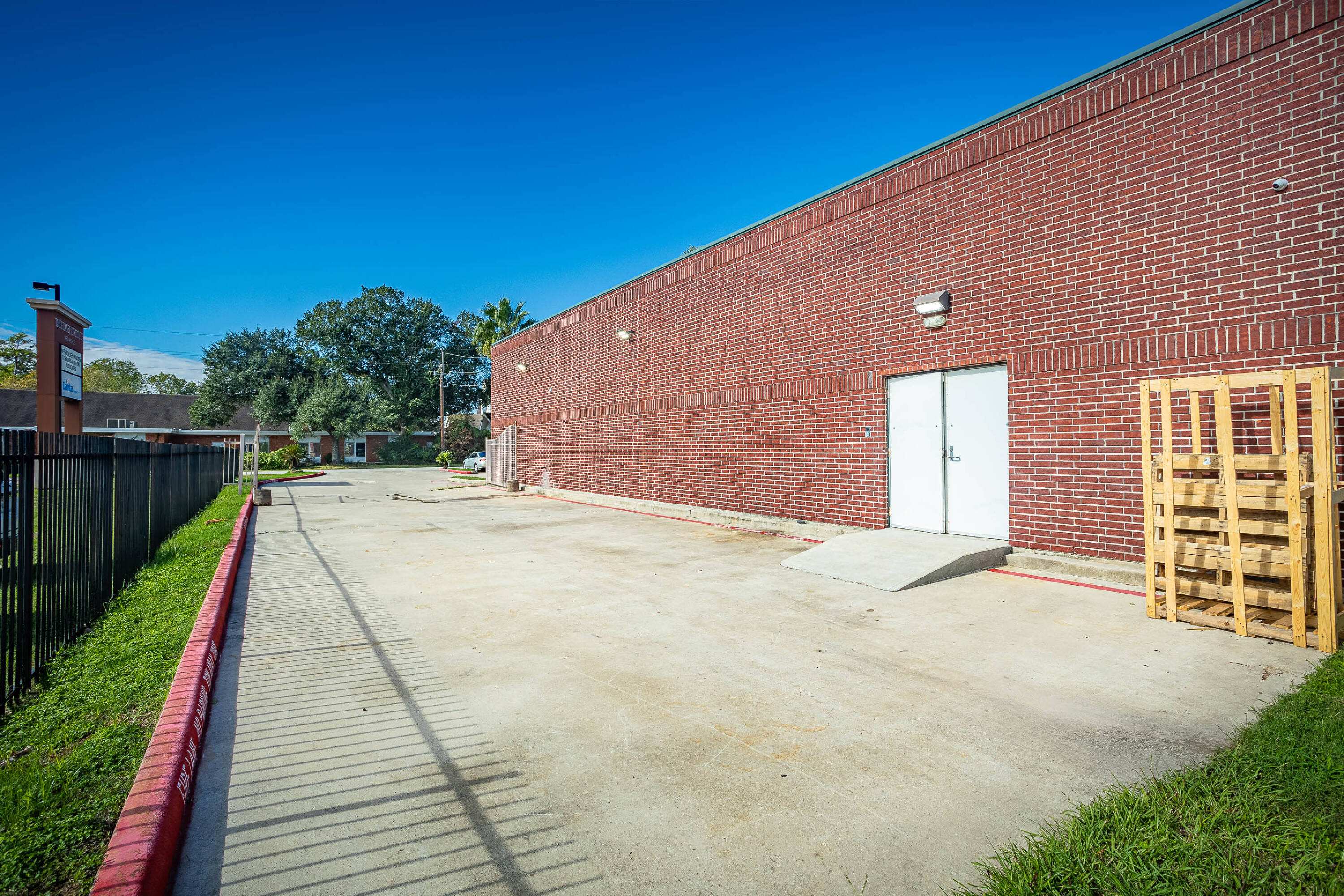 Rear view of a brick warehouse with loading area and secure fencing at 16920 Mathis Church Rd, Houston, TX.