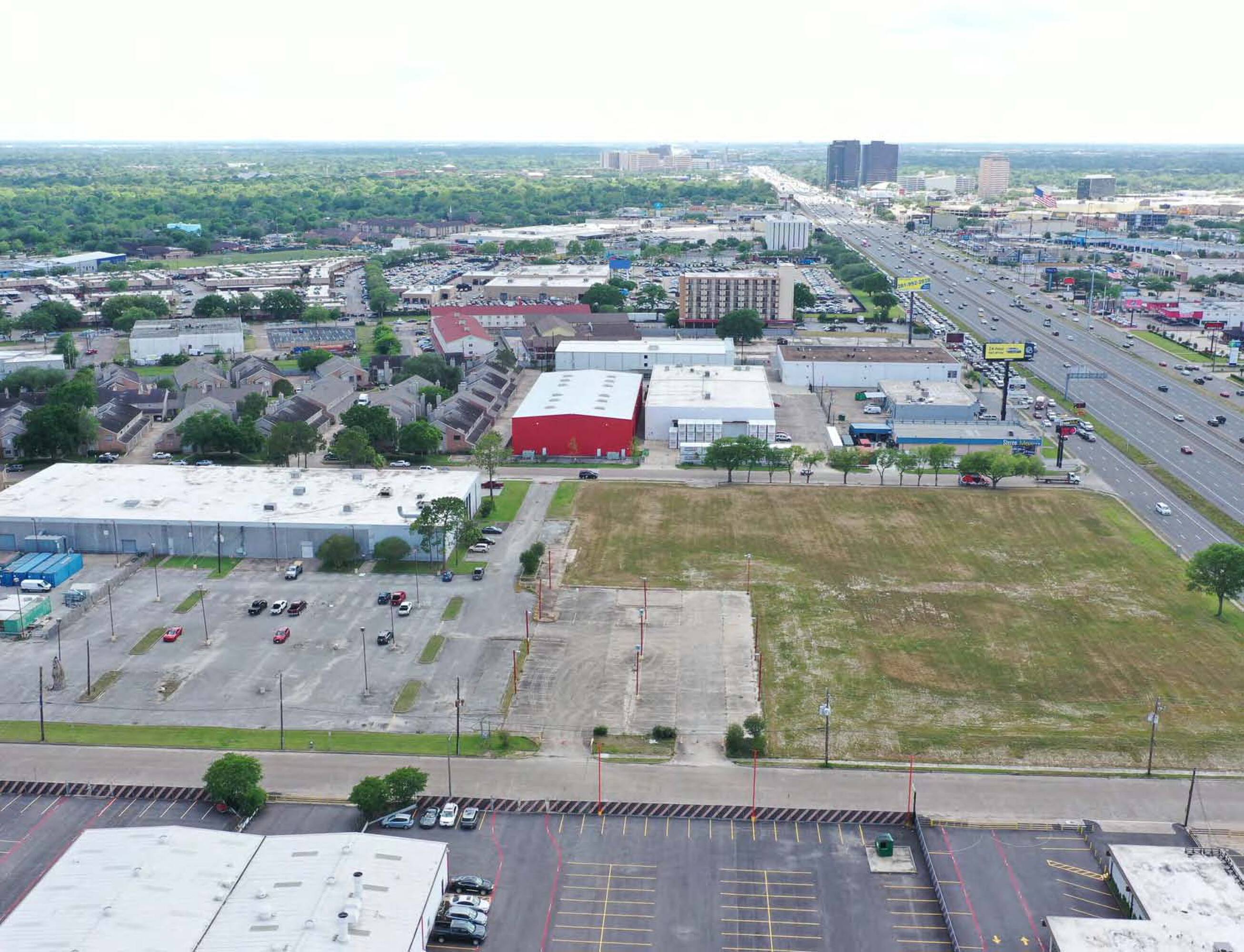 Aerial view of a large vacant land parcel at 6767 Southwest Fwy, Houston, TX, surrounded by commercial buildings and adjacent to a highway.