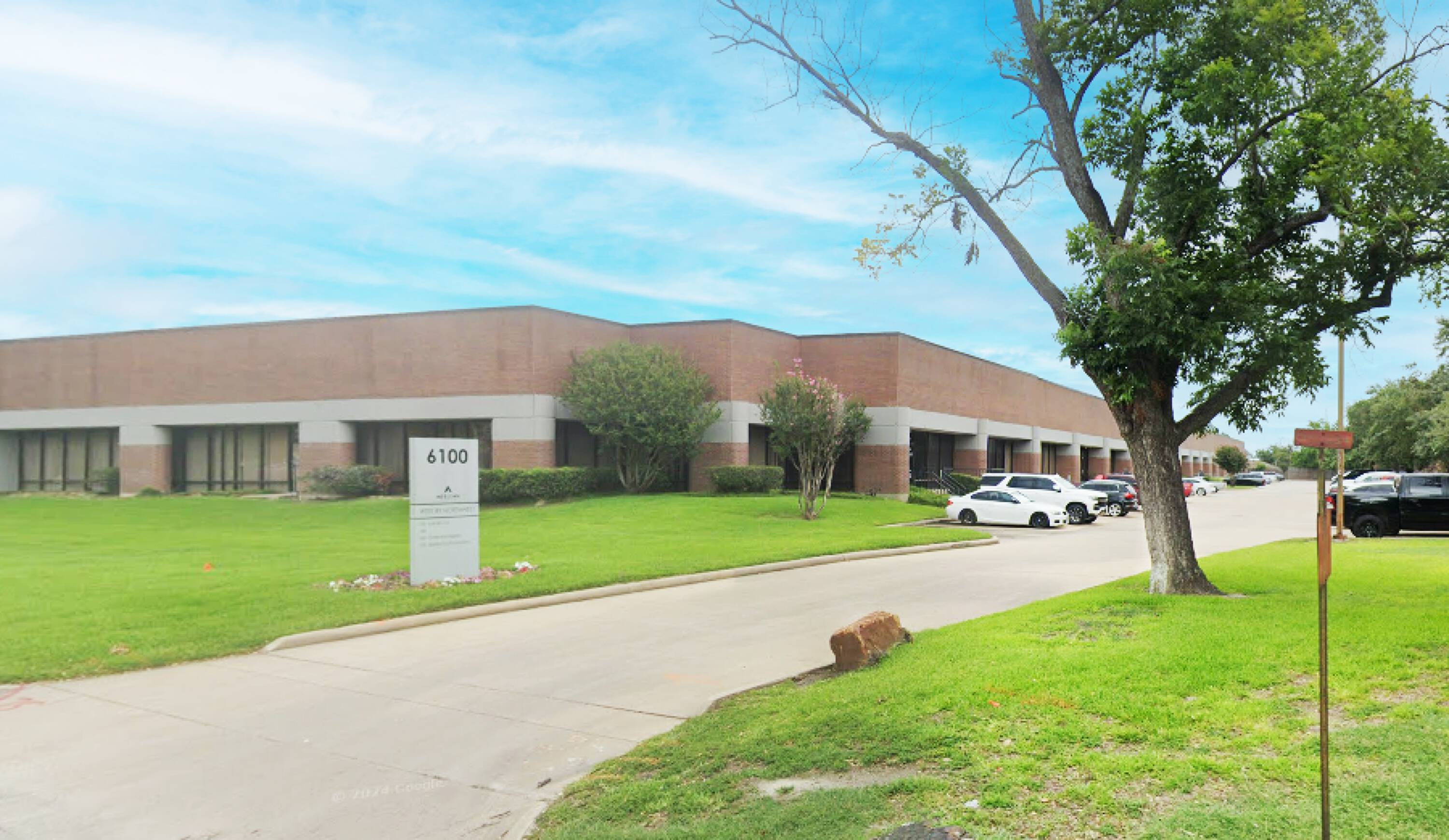 A well-maintained Class B office/warehouse building with brick facade, large windows, and surface parking lot.