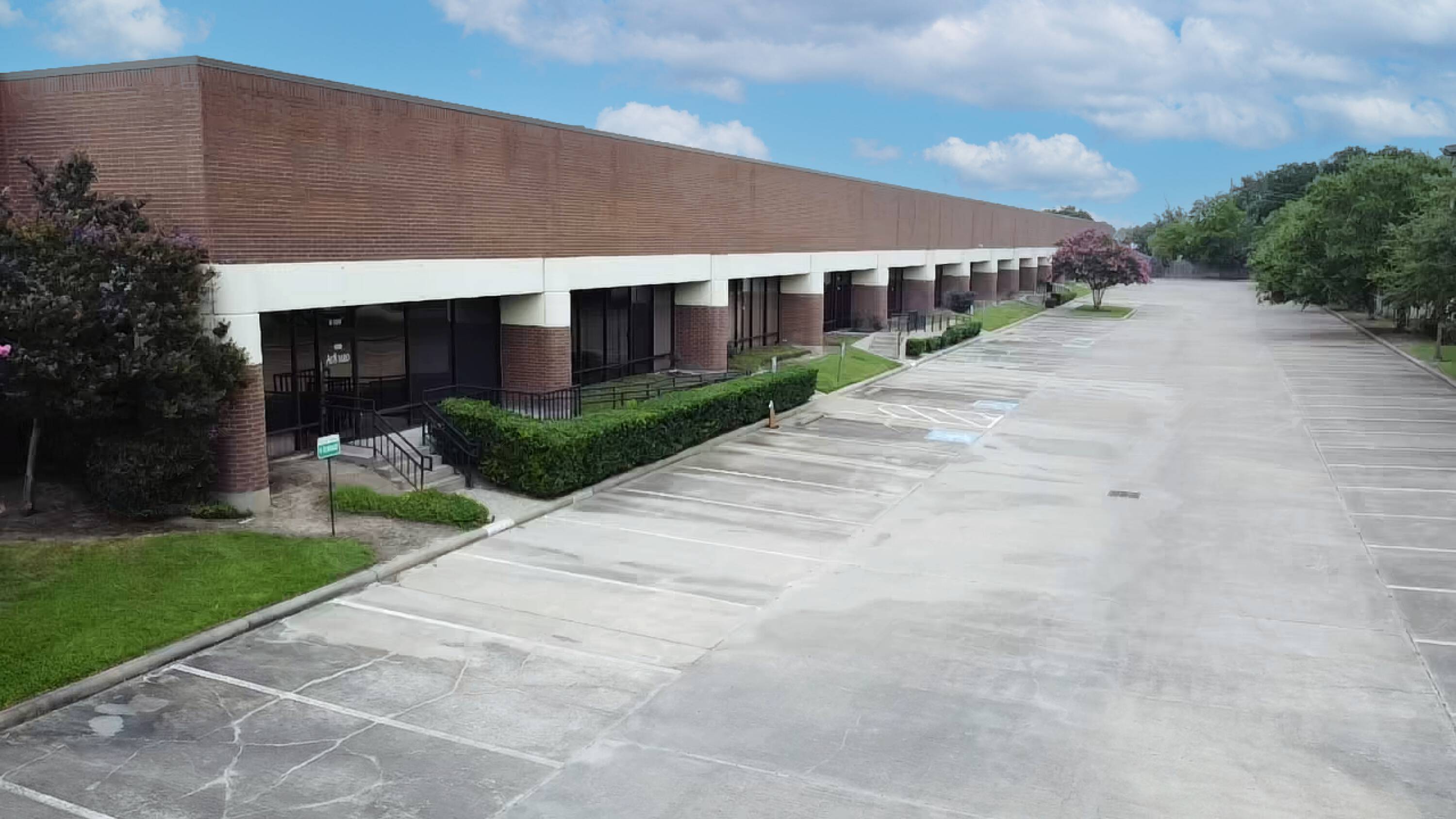 Aerial view of a single-story commercial building with brick facade, large windows, and surface parking lot.