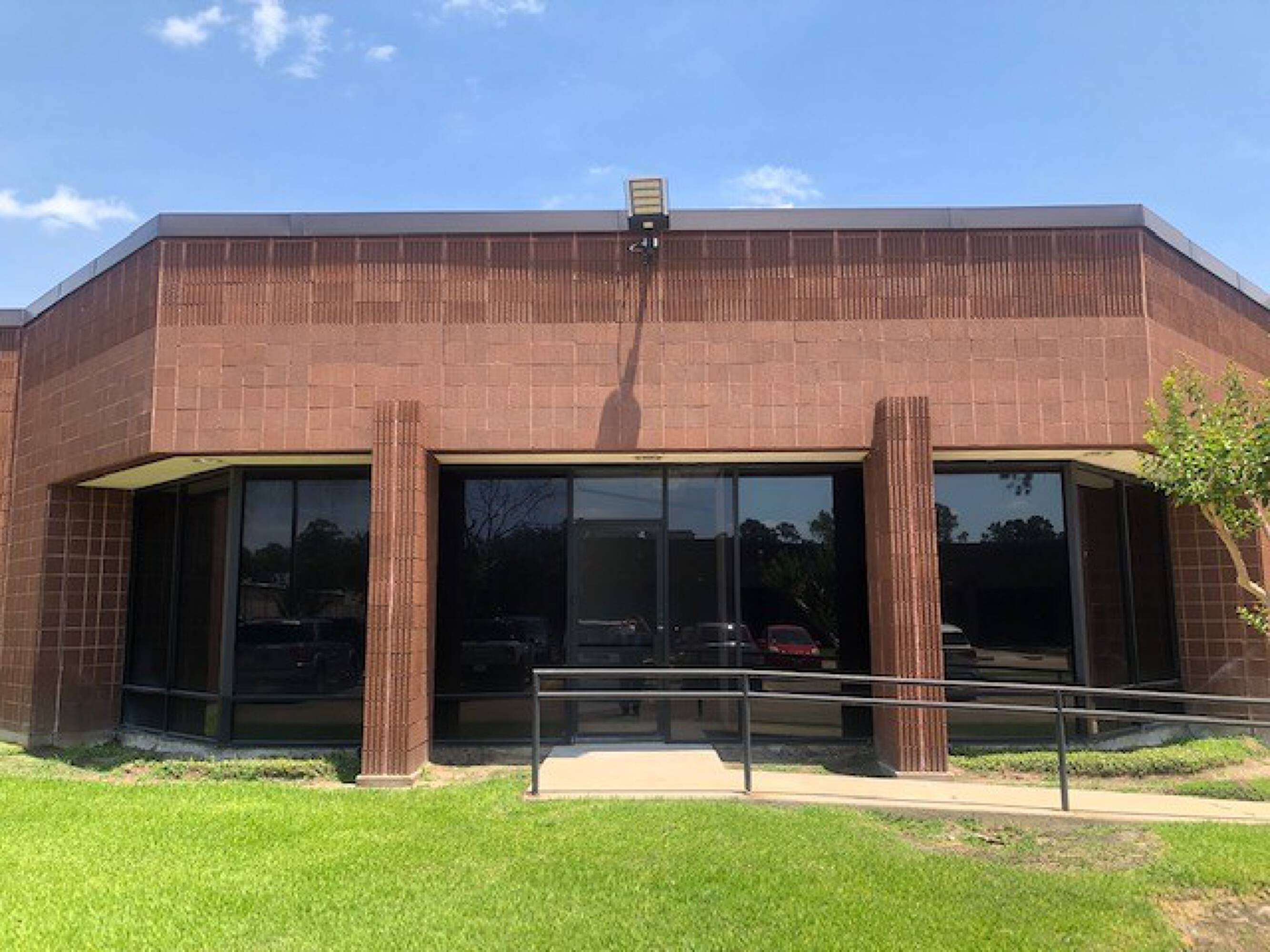 Modern brick commercial building with large windows and a central entrance featuring double glass doors.