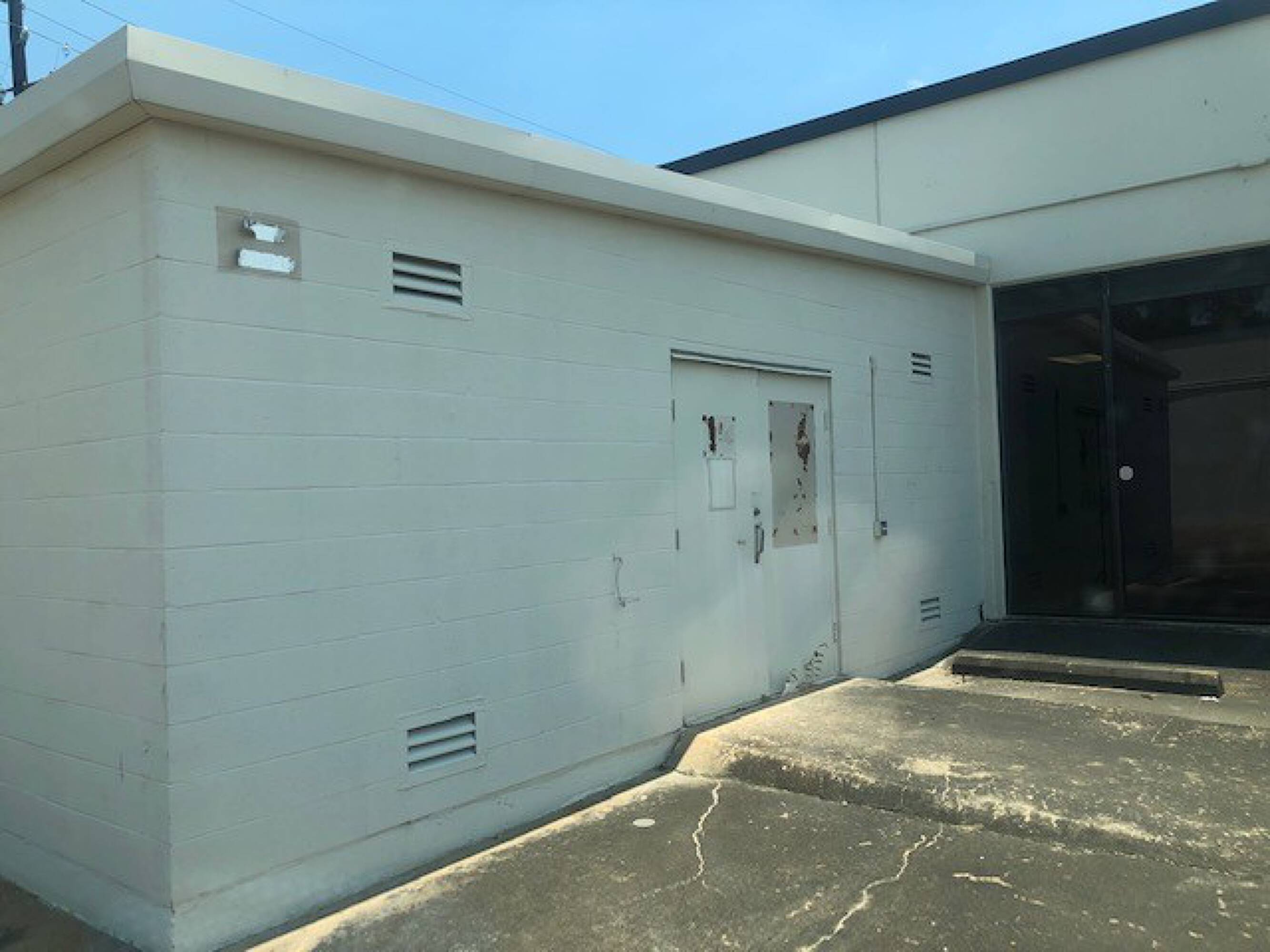 Industrial building with secure access, concrete loading area, and adjacent modern commercial building.