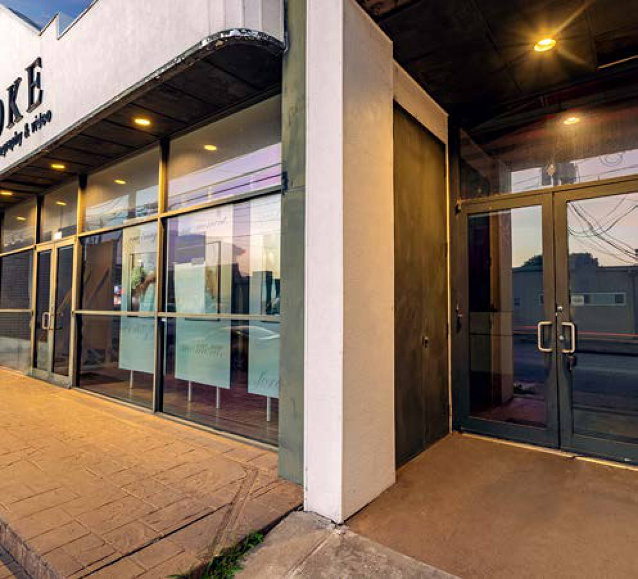 Modern retail and office building with large glass windows and double door entrance on Kelvin Dr, Houston.