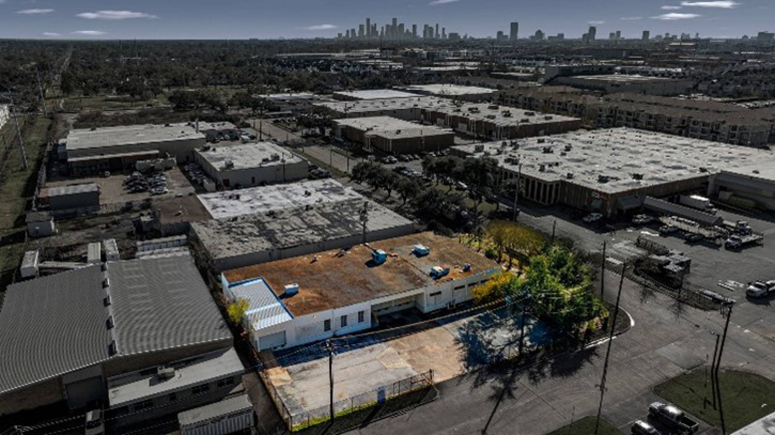 Aerial view of an industrial property at 6880 Wynnwood Lane, Houston, TX, with surrounding buildings and parking.