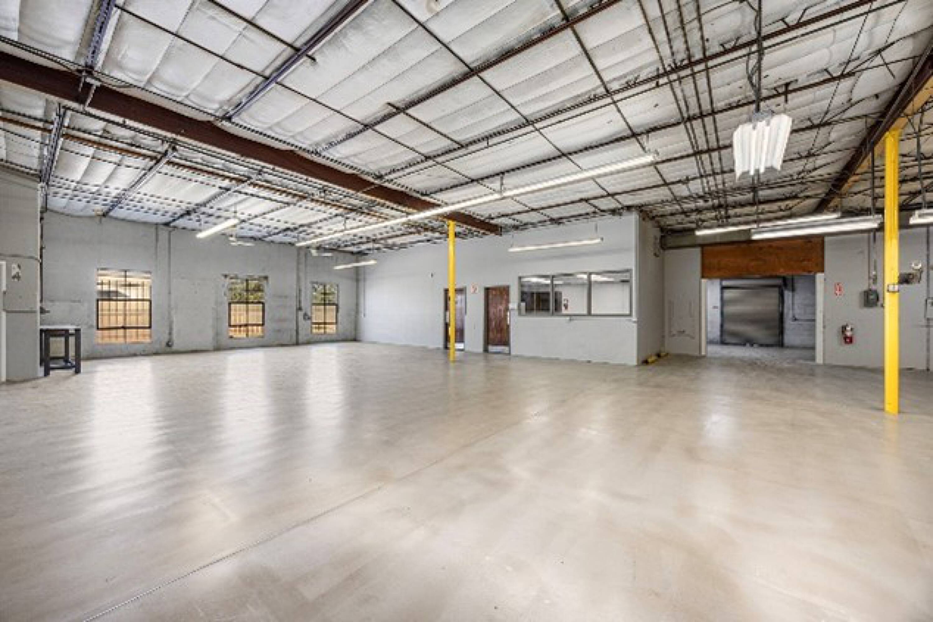 Spacious industrial warehouse with high ceilings, large windows, and a roll-up door at 6880 Wynnwood Lane, Houston, TX.