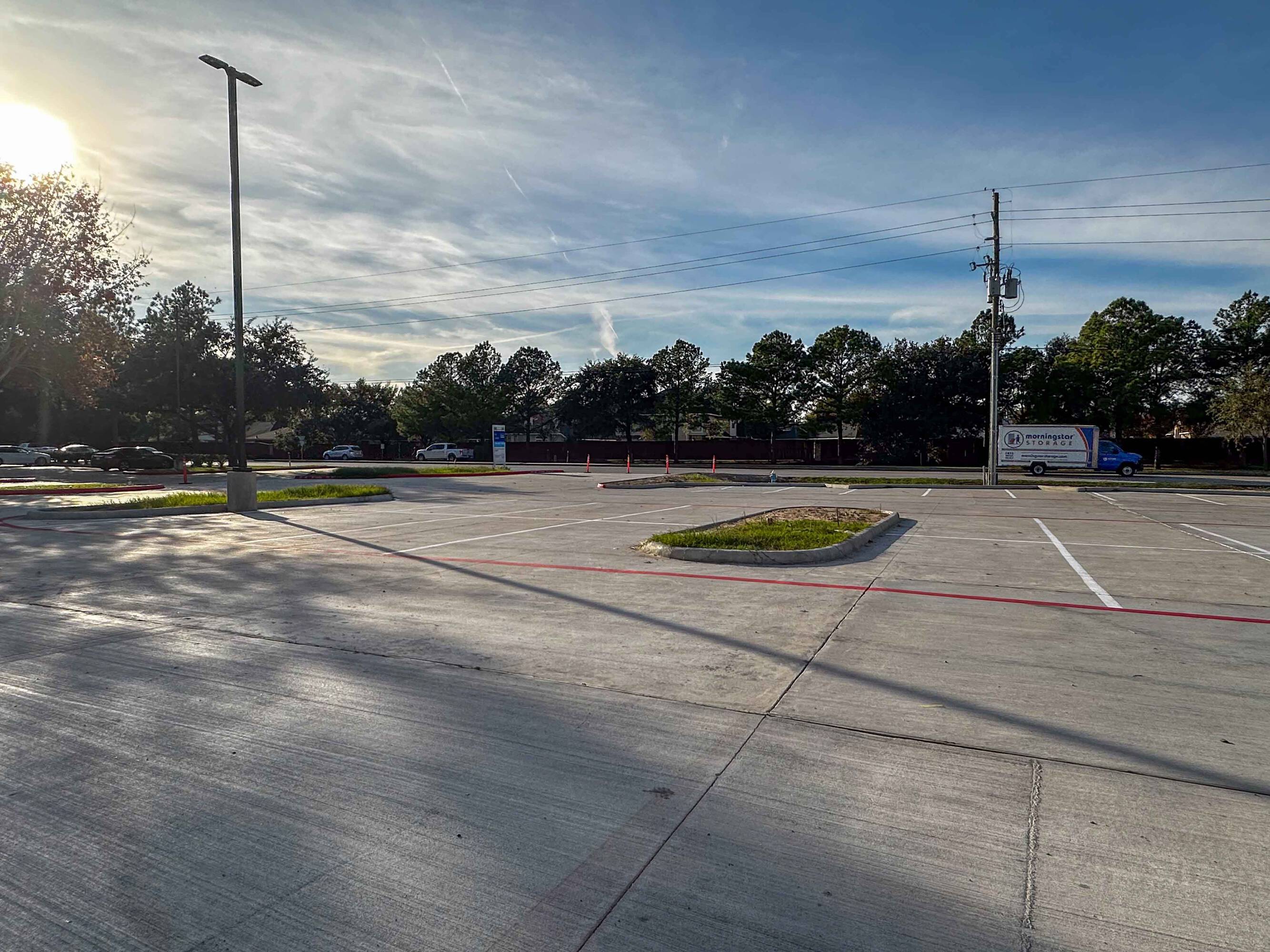 Spacious parking lot with modern retail buildings and ample natural light at The Shoppes at Riata Heights.