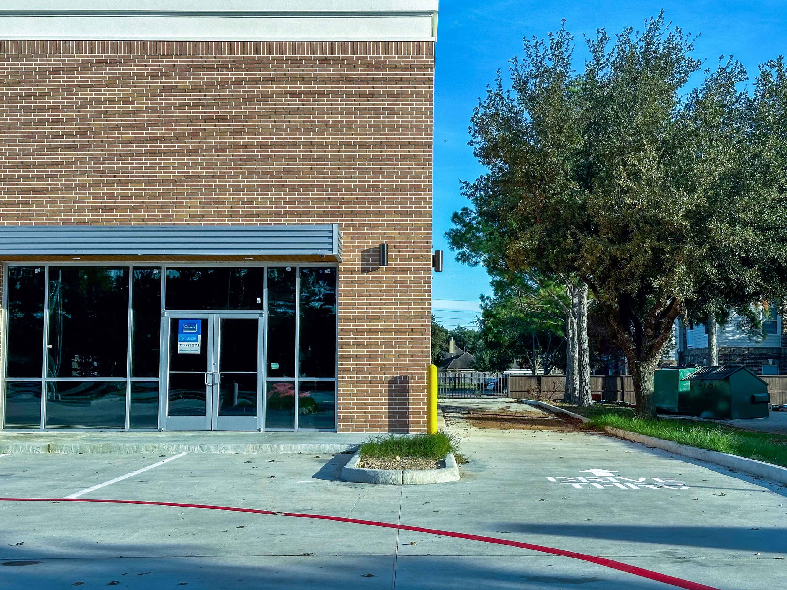 The Shoppes at Riata Heights retail property with brick facade, large glass windows, and surface parking.