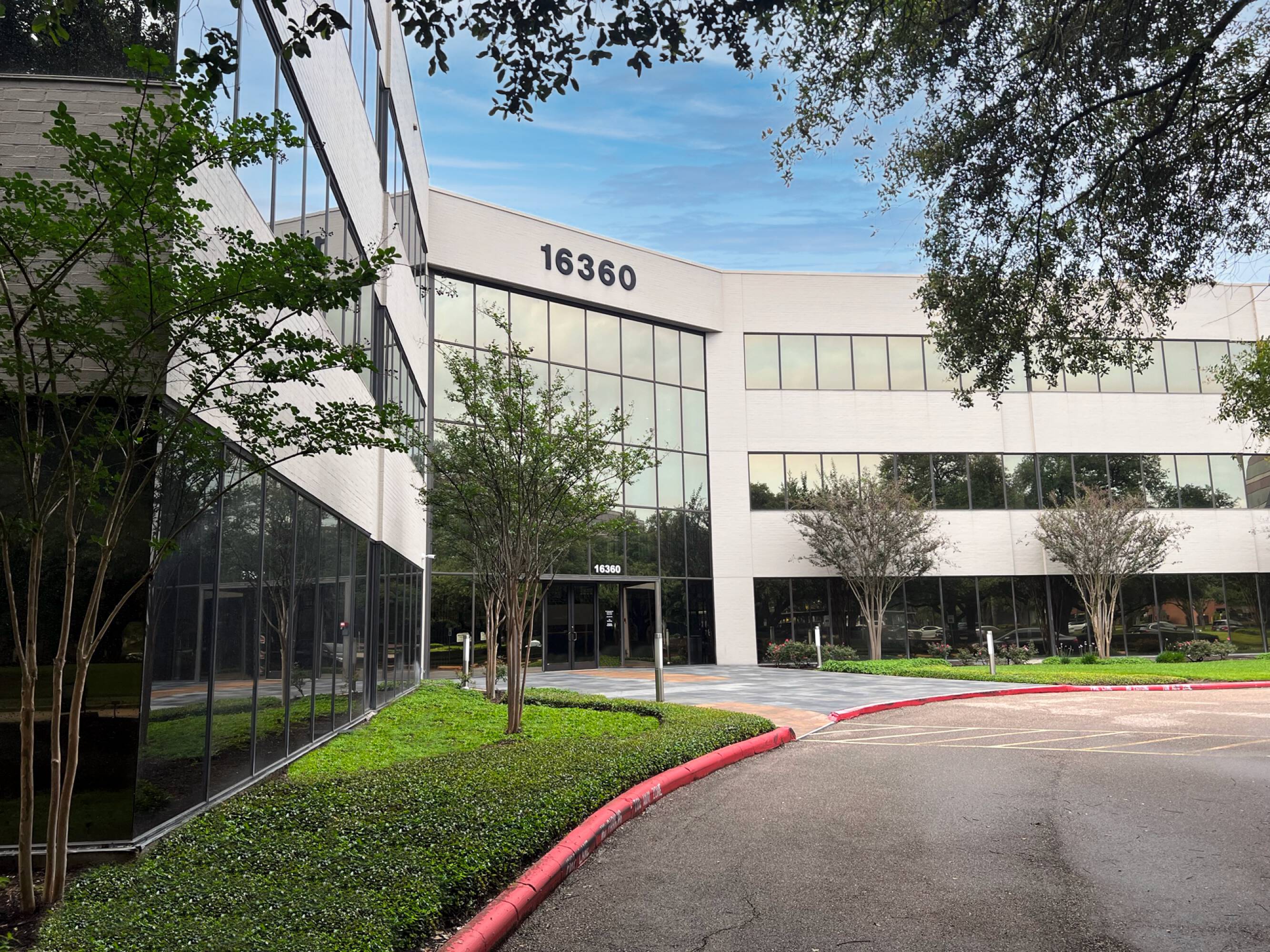 Modern three-story office building with large windows and surface parking at Sixteen 360 Park Ten Place in Houston, TX.