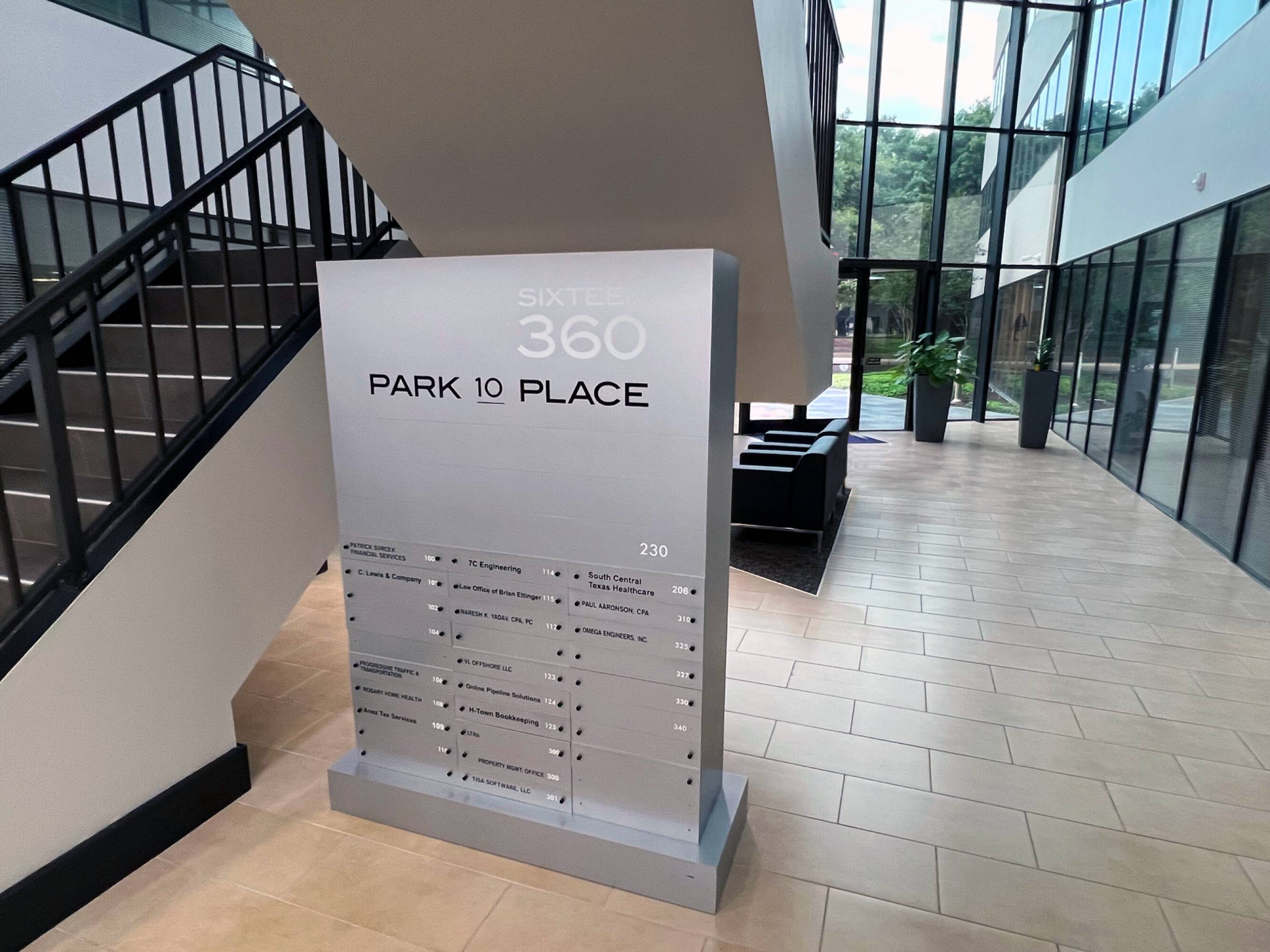 Modern office lobby with large windows, directory sign, and glass doors at Sixteen 360 Park Ten Place.