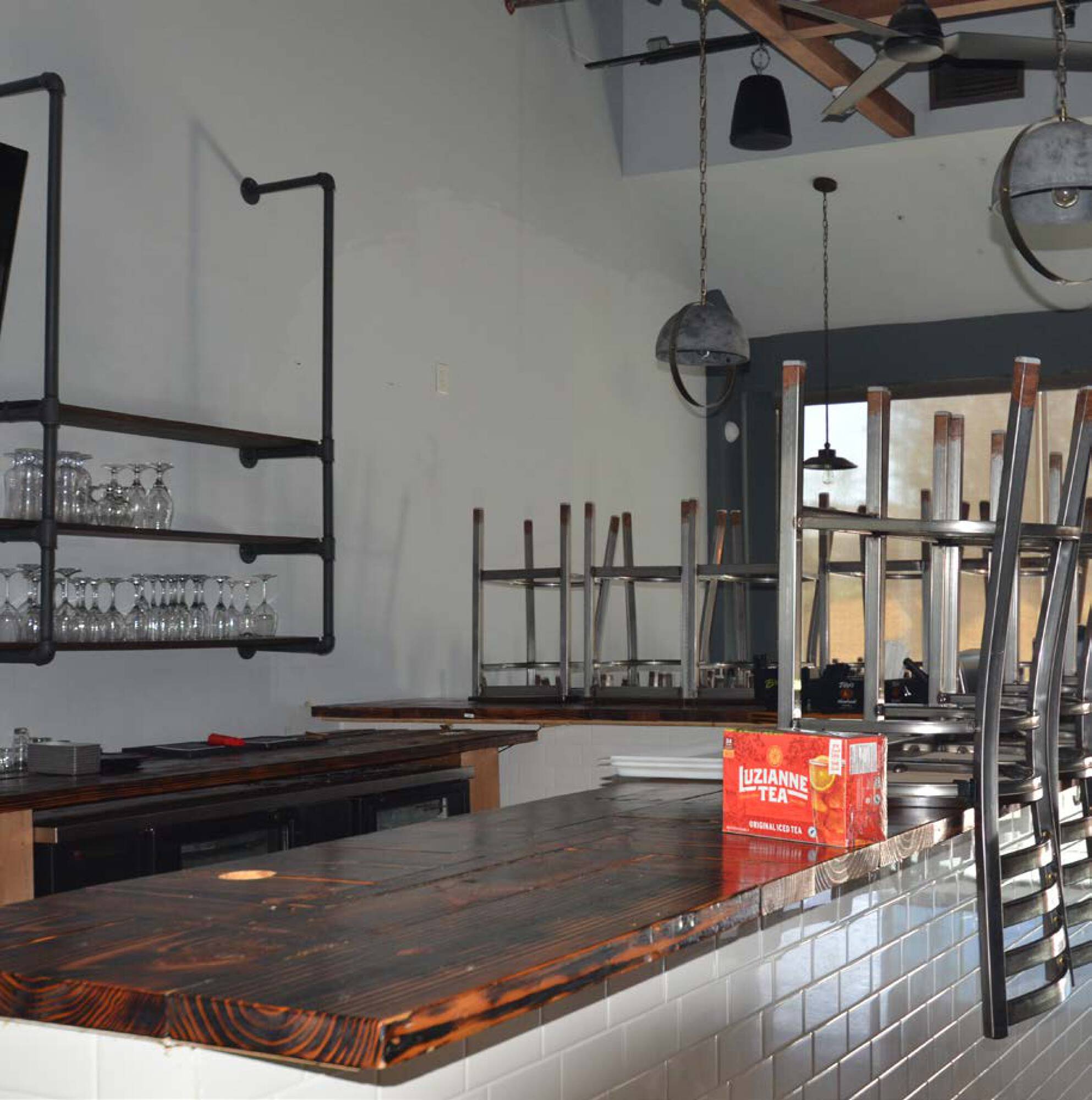 Modern industrial-style interior with a wooden bar, metal shelving, and exposed lighting fixtures.