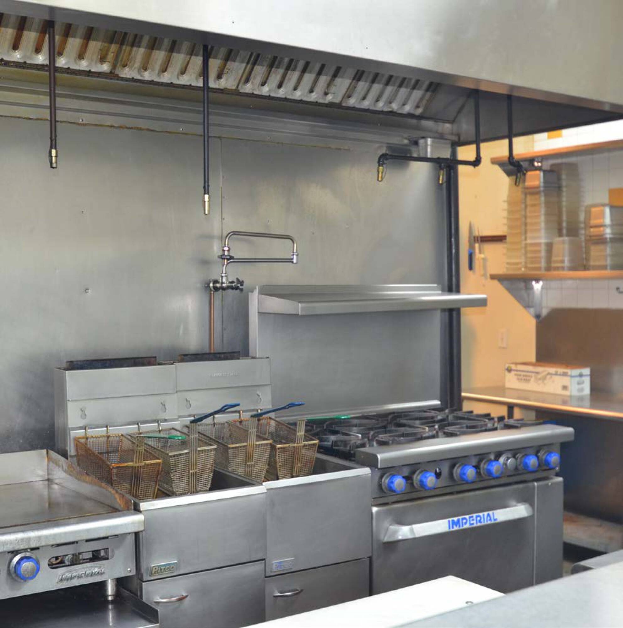 A well-maintained commercial kitchen with stainless steel surfaces, fryers, stovetops, and ventilation systems.