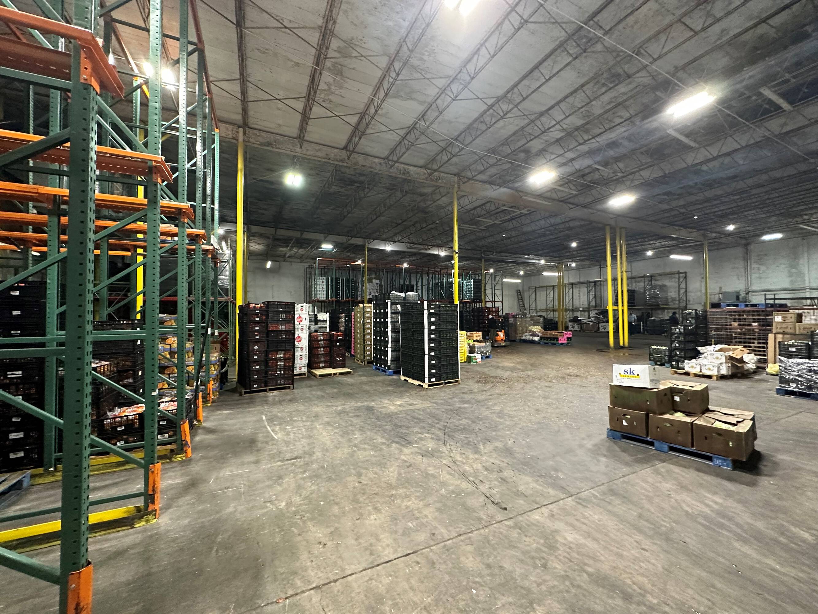 Spacious industrial warehouse with high ceilings, ample lighting, and organized storage shelving.