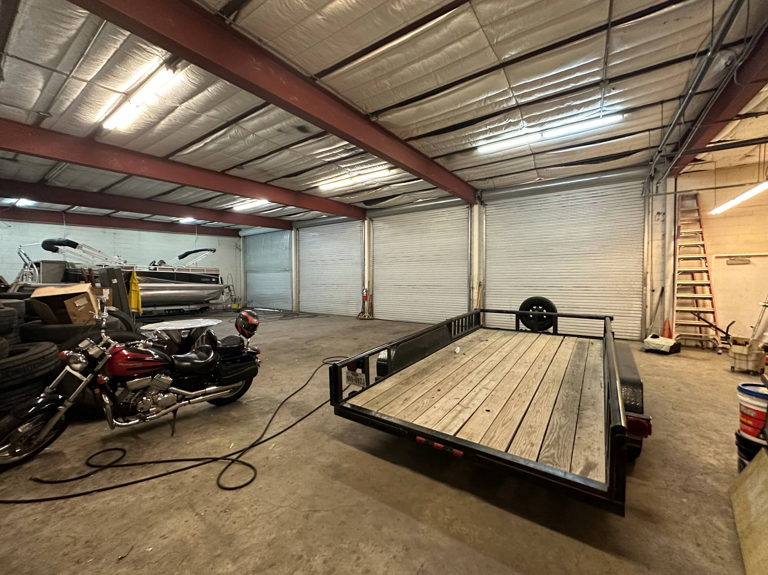 Interior of an industrial warehouse at 2216 Silver Street, Houston, TX, featuring high ceilings, fluorescent lighting, and a trailer.