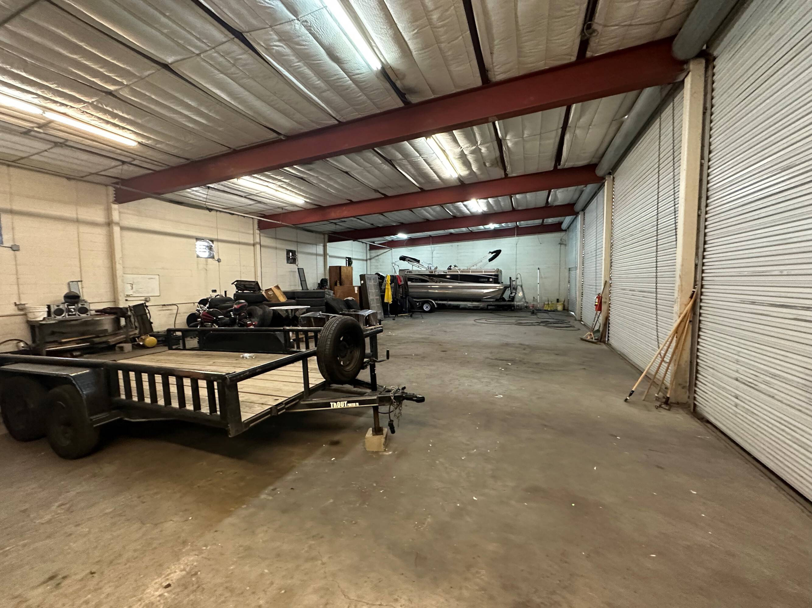Interior view of an industrial warehouse with high ceilings, roll-up doors, and a trailer inside.