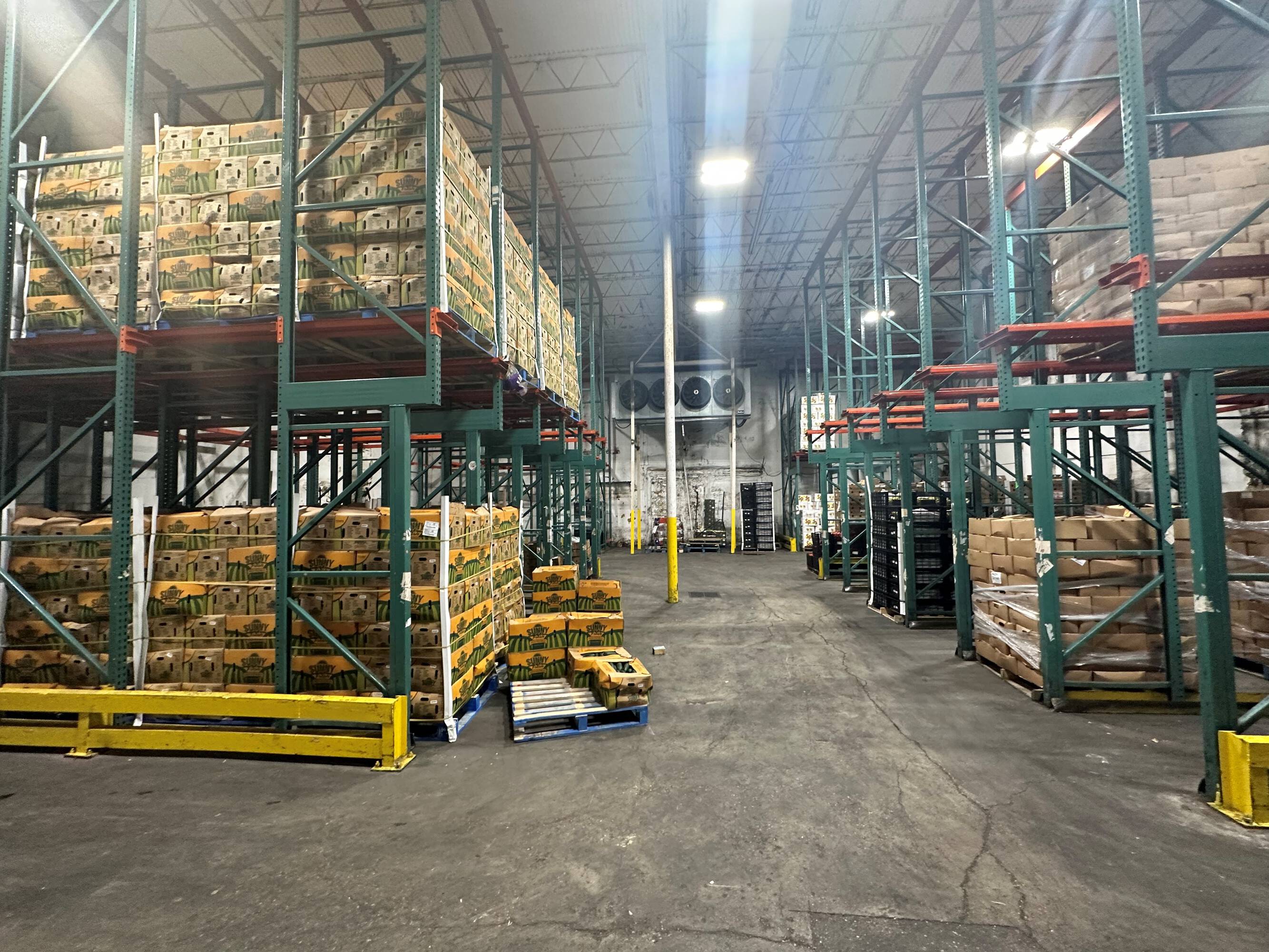Interior view of a well-lit industrial warehouse with high ceilings and organized storage shelving.