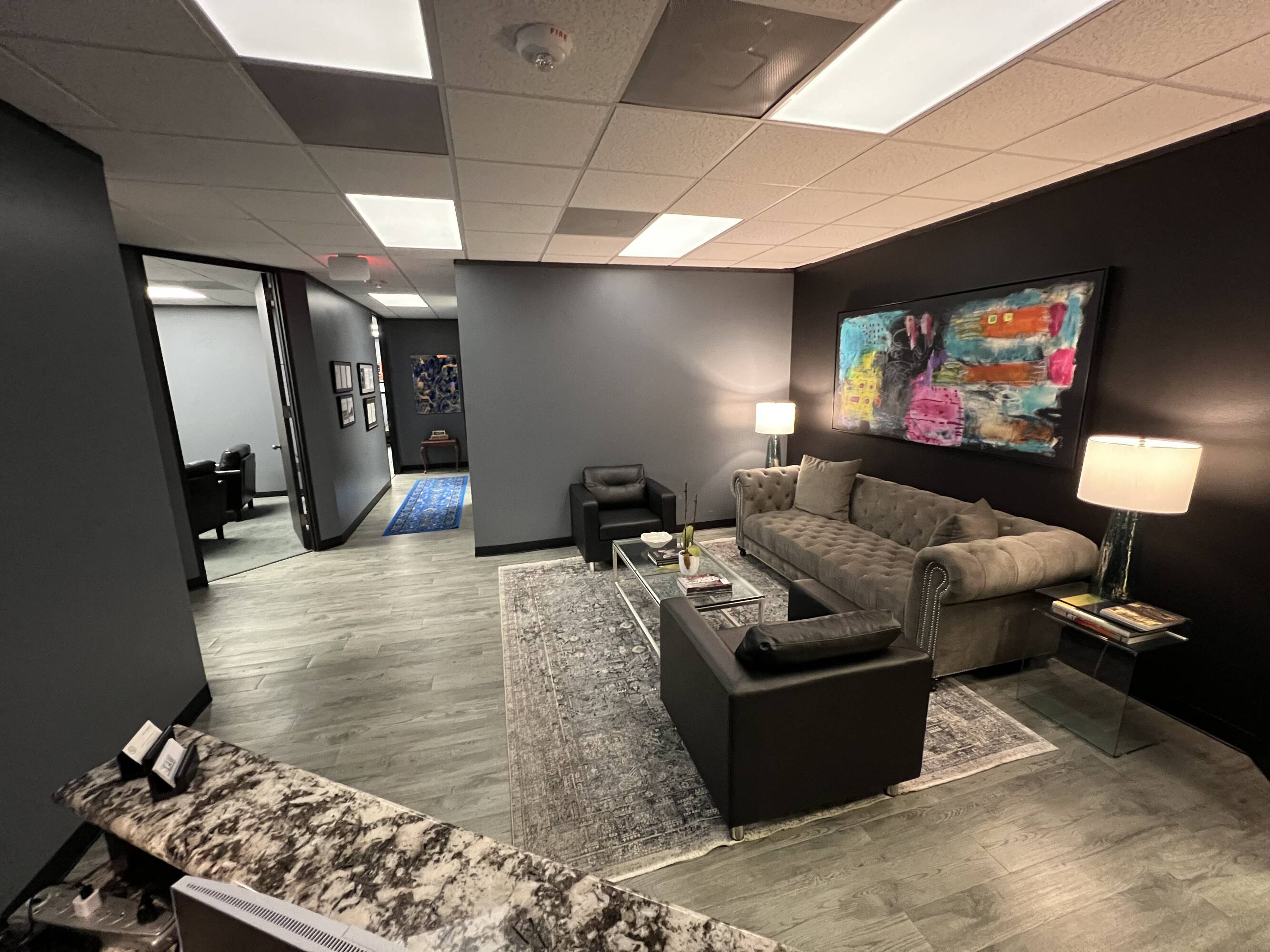 Modern law office reception area with comfortable seating, natural light, and artistic wall mural.