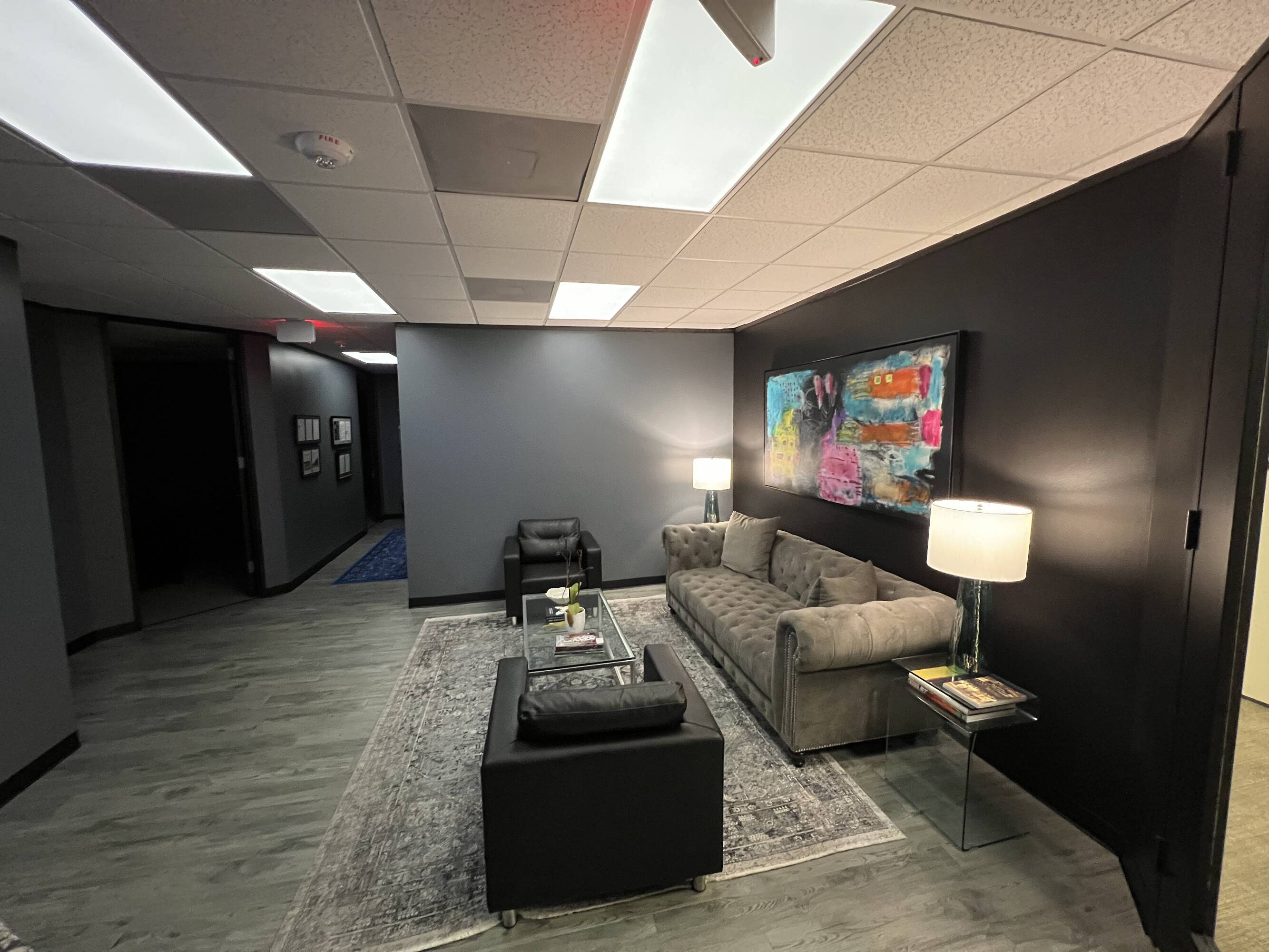 Modern office lounge area with sofa, armchair, coffee table, and artistic wall decor at Law Office of Sean Buckley, Woodway Center.