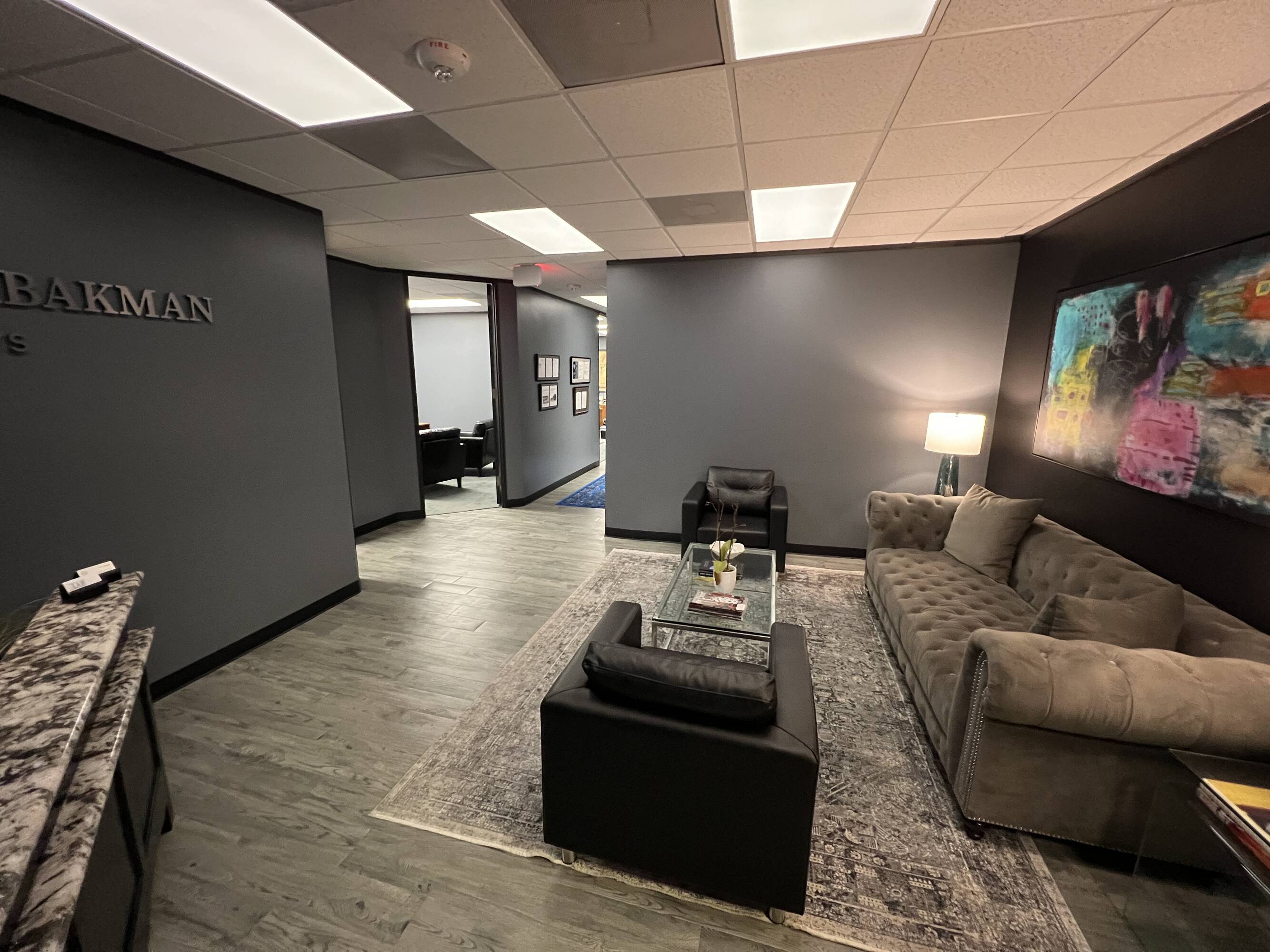 Modern office reception area with comfortable seating, large windows, and contemporary decor.