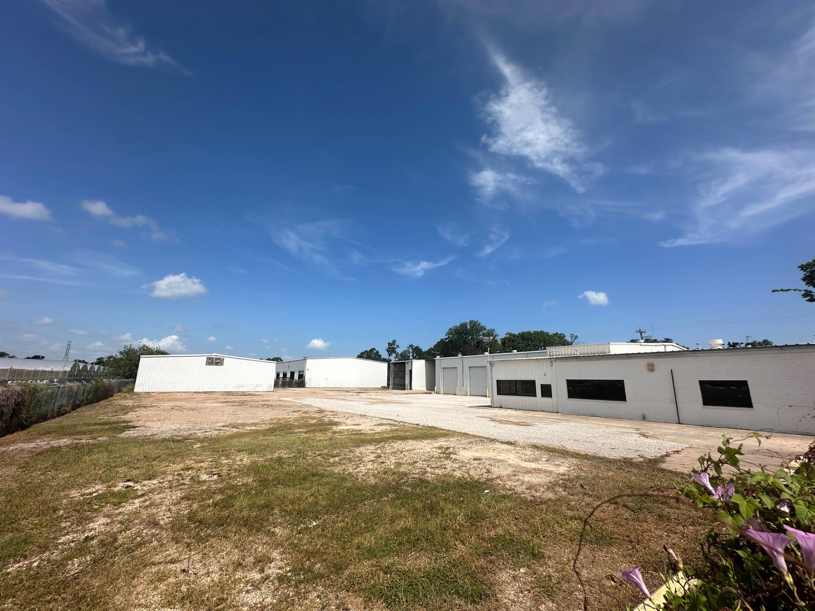 Exterior view of Brittmoore Business Park with white buildings, large windows, and open parking area.