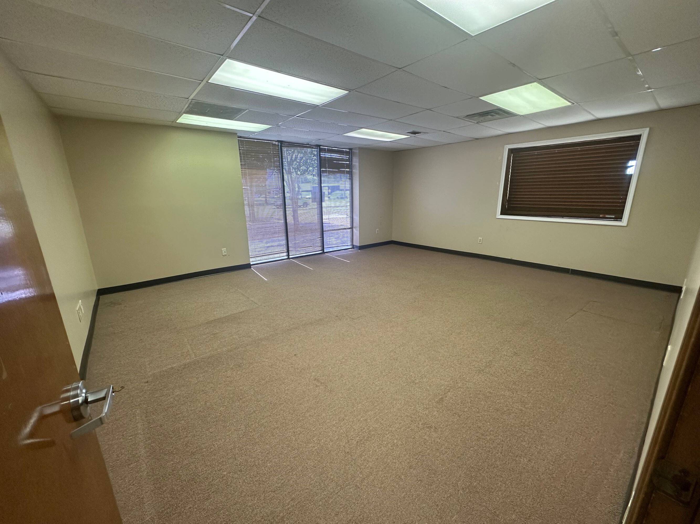 Empty office space with large windows, carpeted floor, and recessed lighting at Brittmoore Business Park.