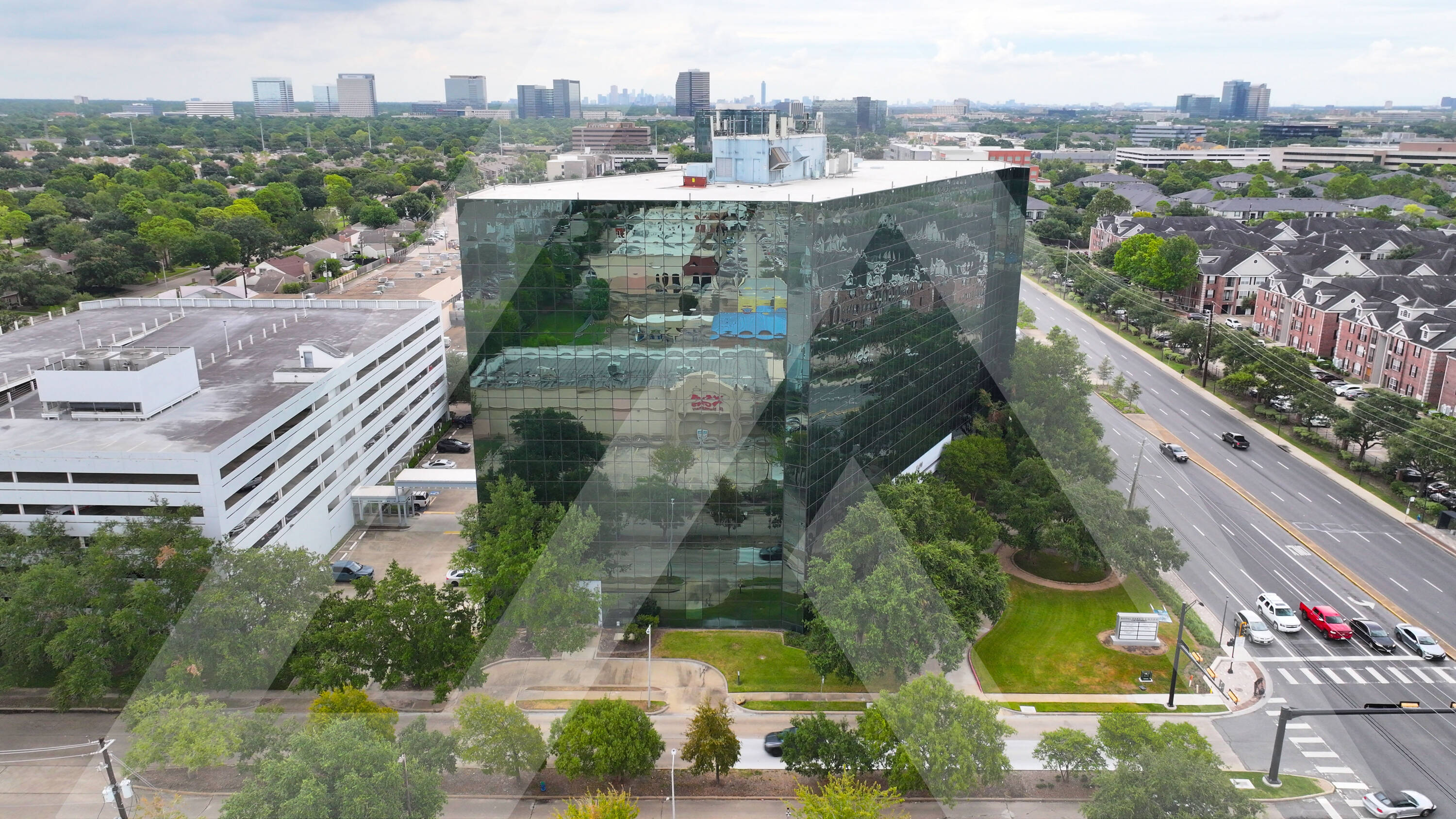 Aerial view of Royal Oaks Centre with modern glass facade and surrounding parking in Houston, TX.