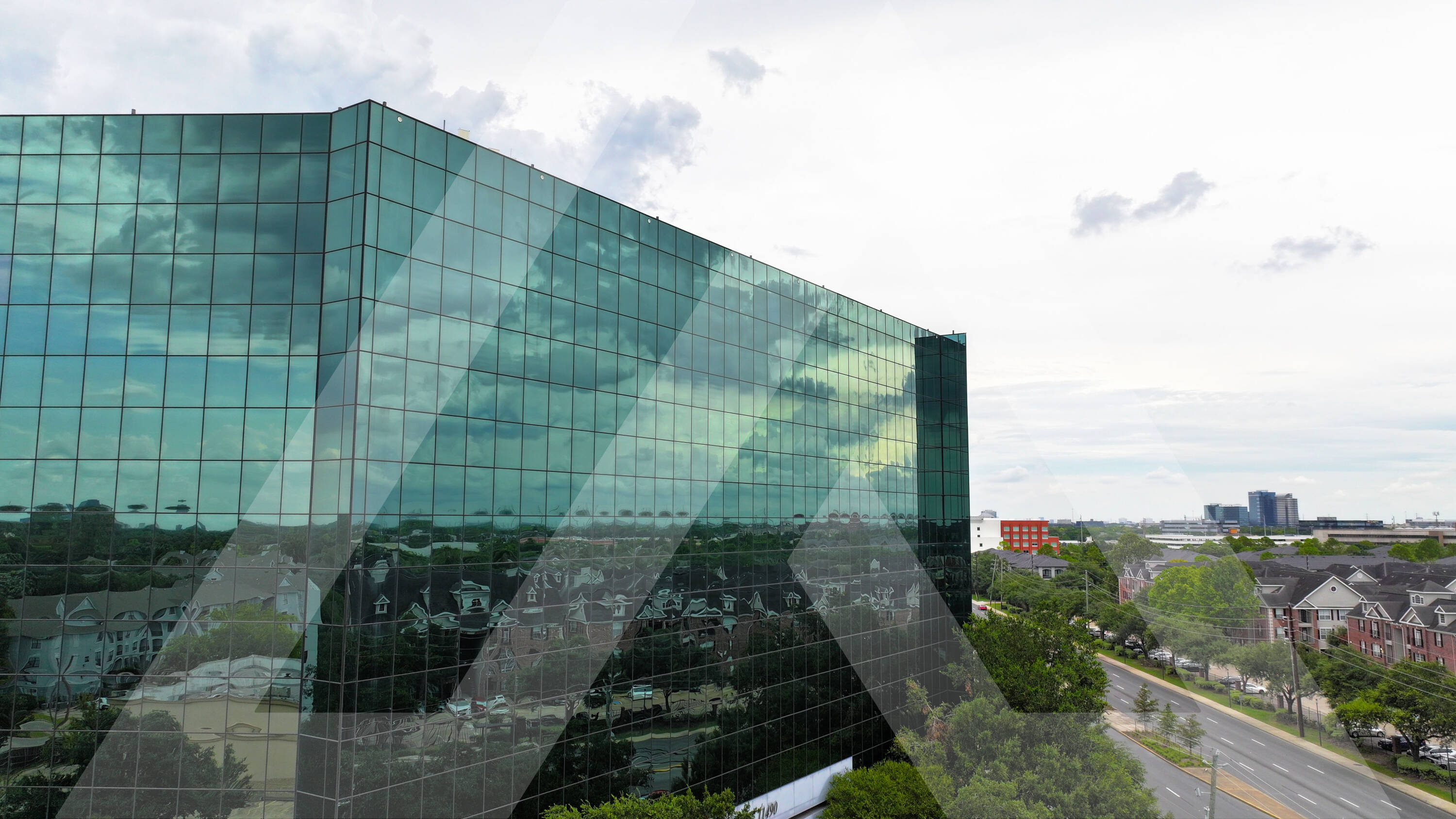 Aerial view of Royal Oaks Centre, a modern retail property with large glass windows and surface parking in Houston, TX.