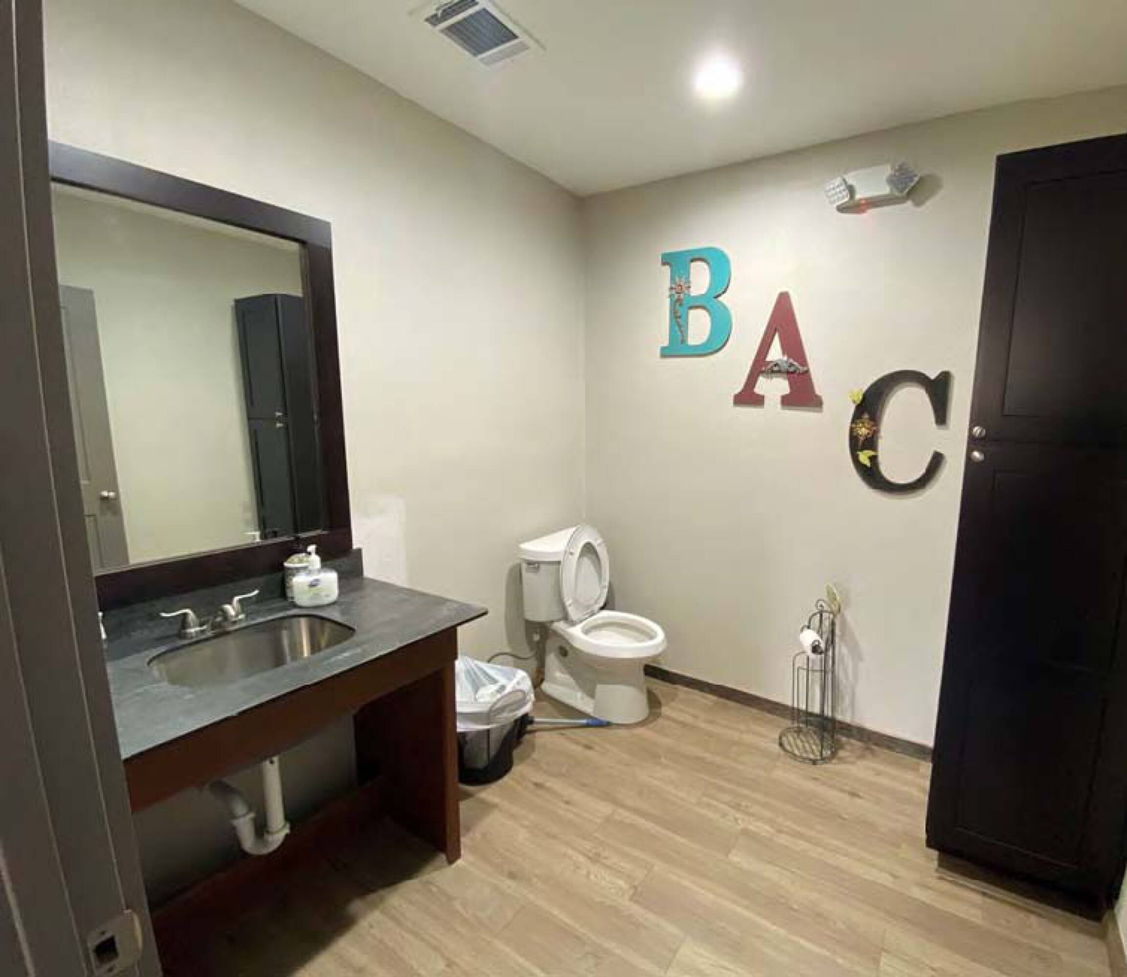 Modern restroom with wood-look flooring, recessed lighting, and decorative wall art at James Place Business Park.