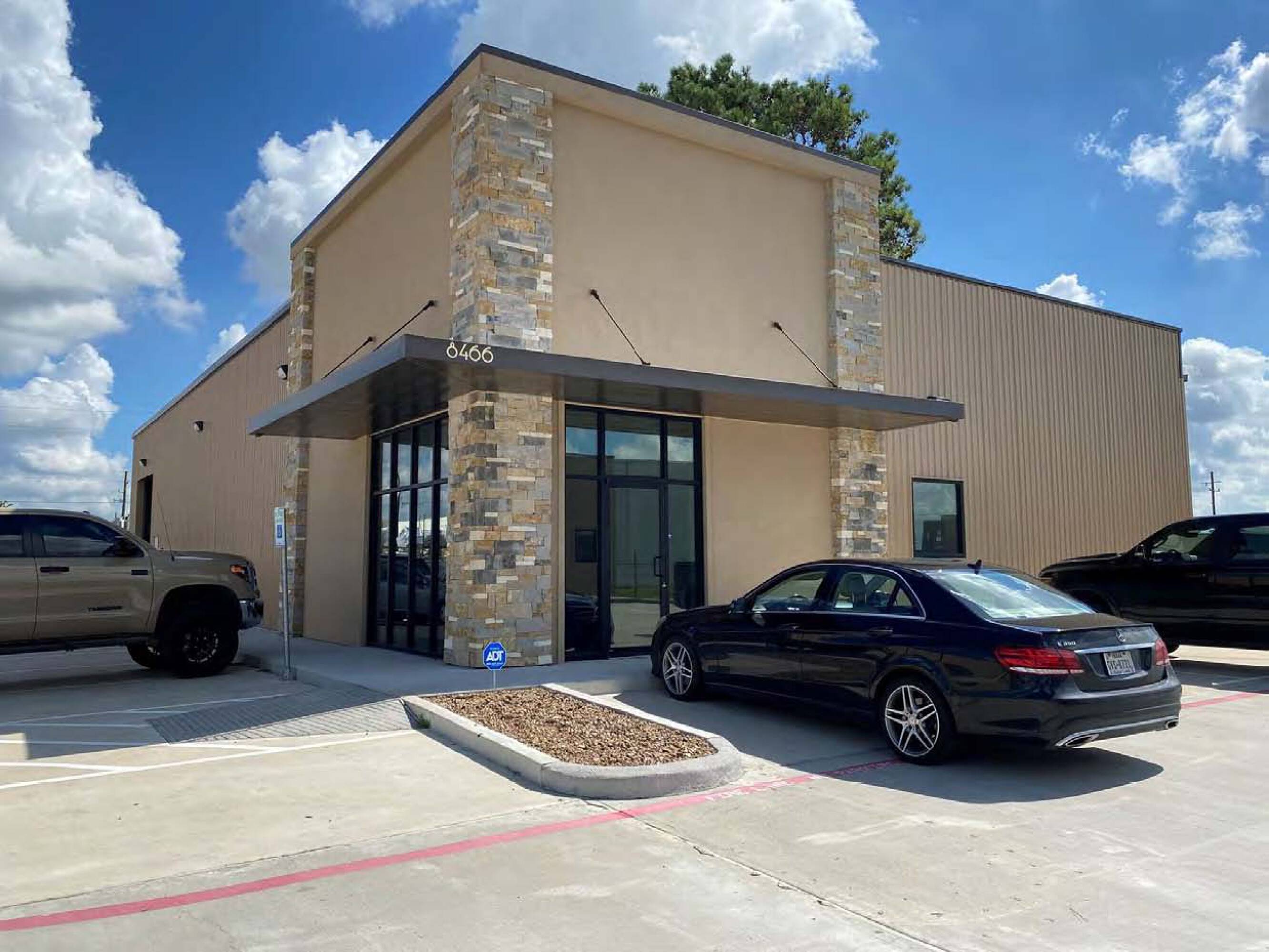 Modern industrial building with stone facade and surface parking at James Place Business Park in Houston, TX.