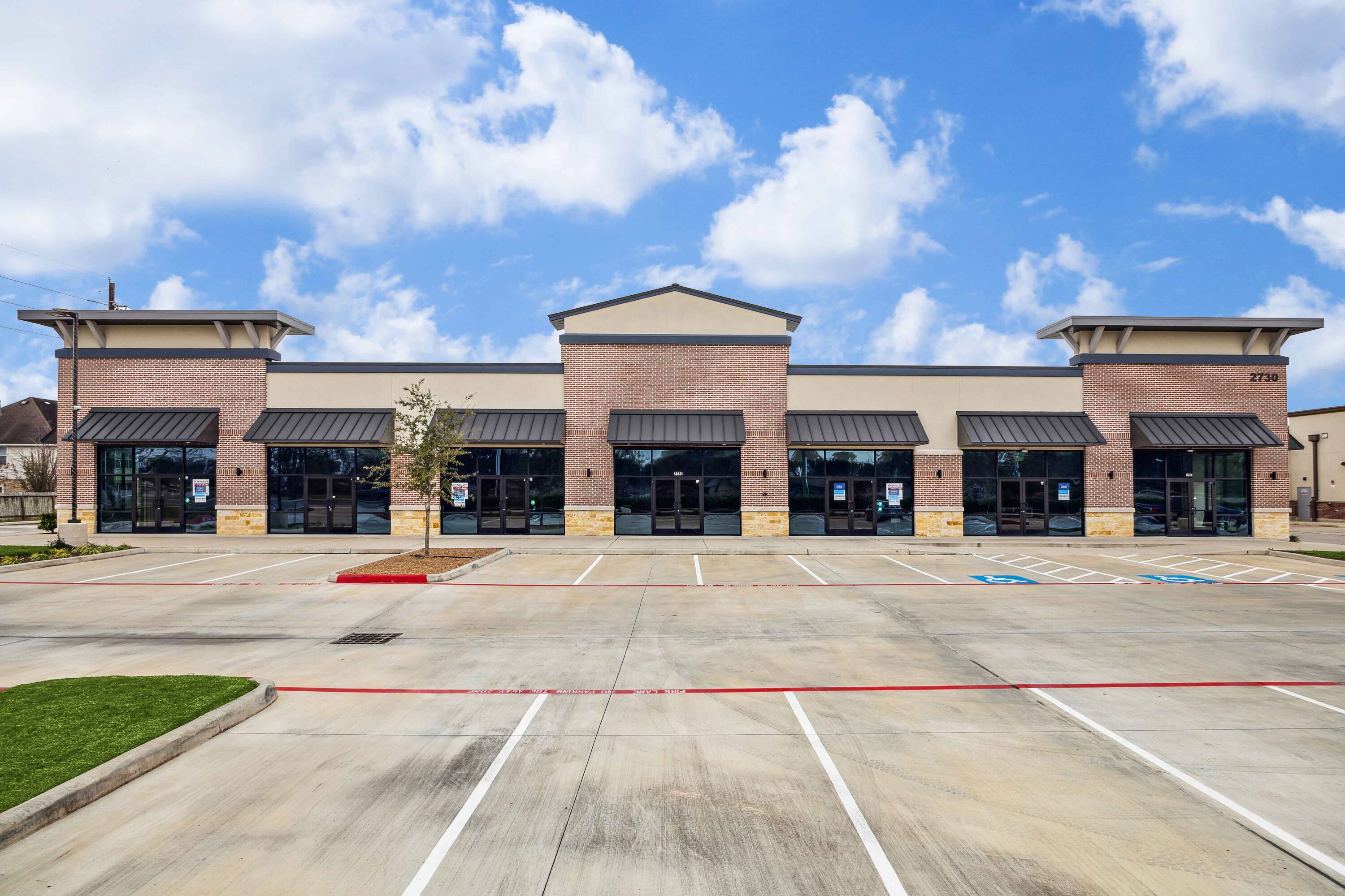 Front view of Plantation Creek Retail Center with multiple storefronts and ample parking.
