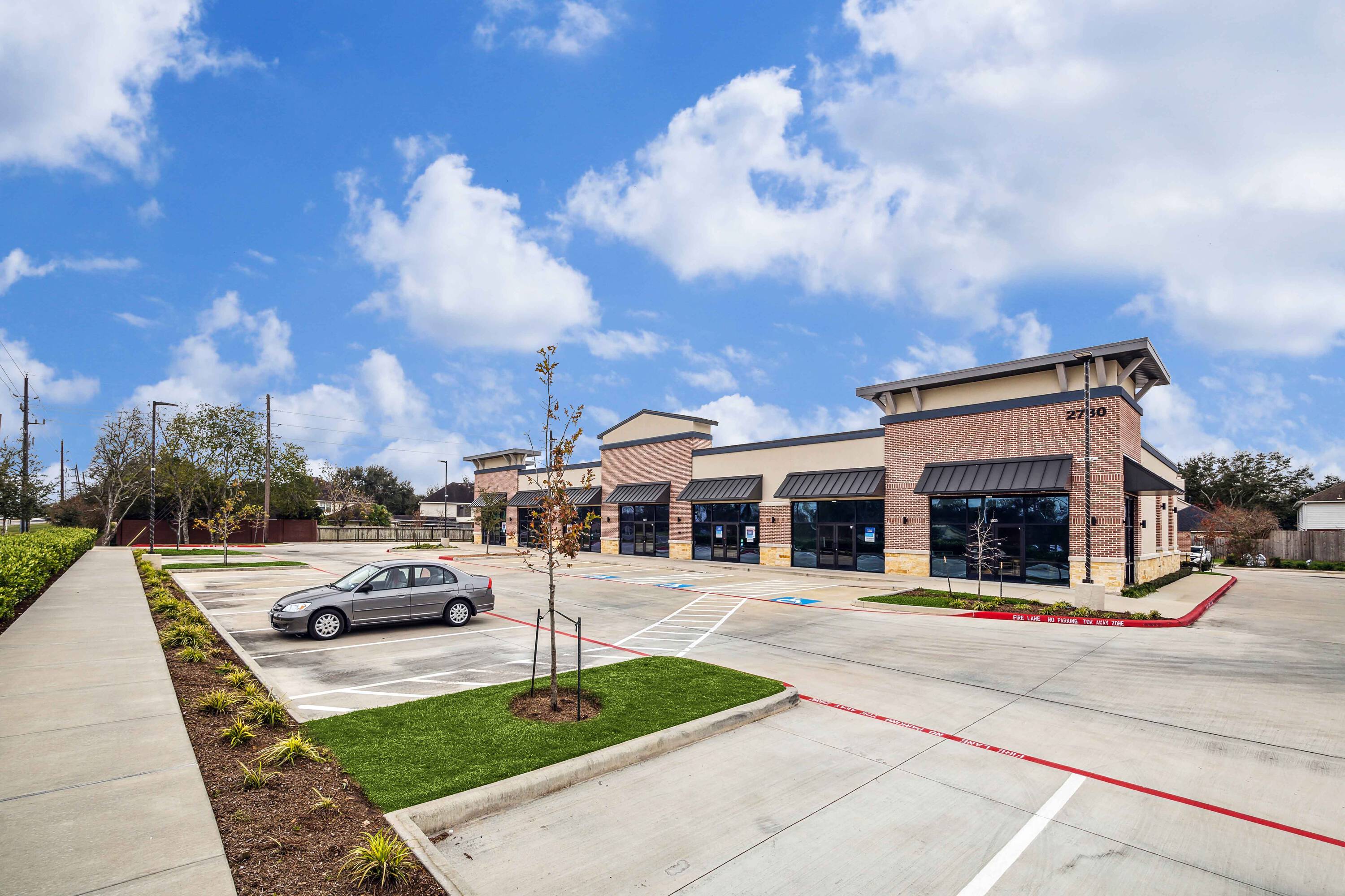 Exterior view of Plantation Creek Retail Center with ample parking and modern storefronts.
