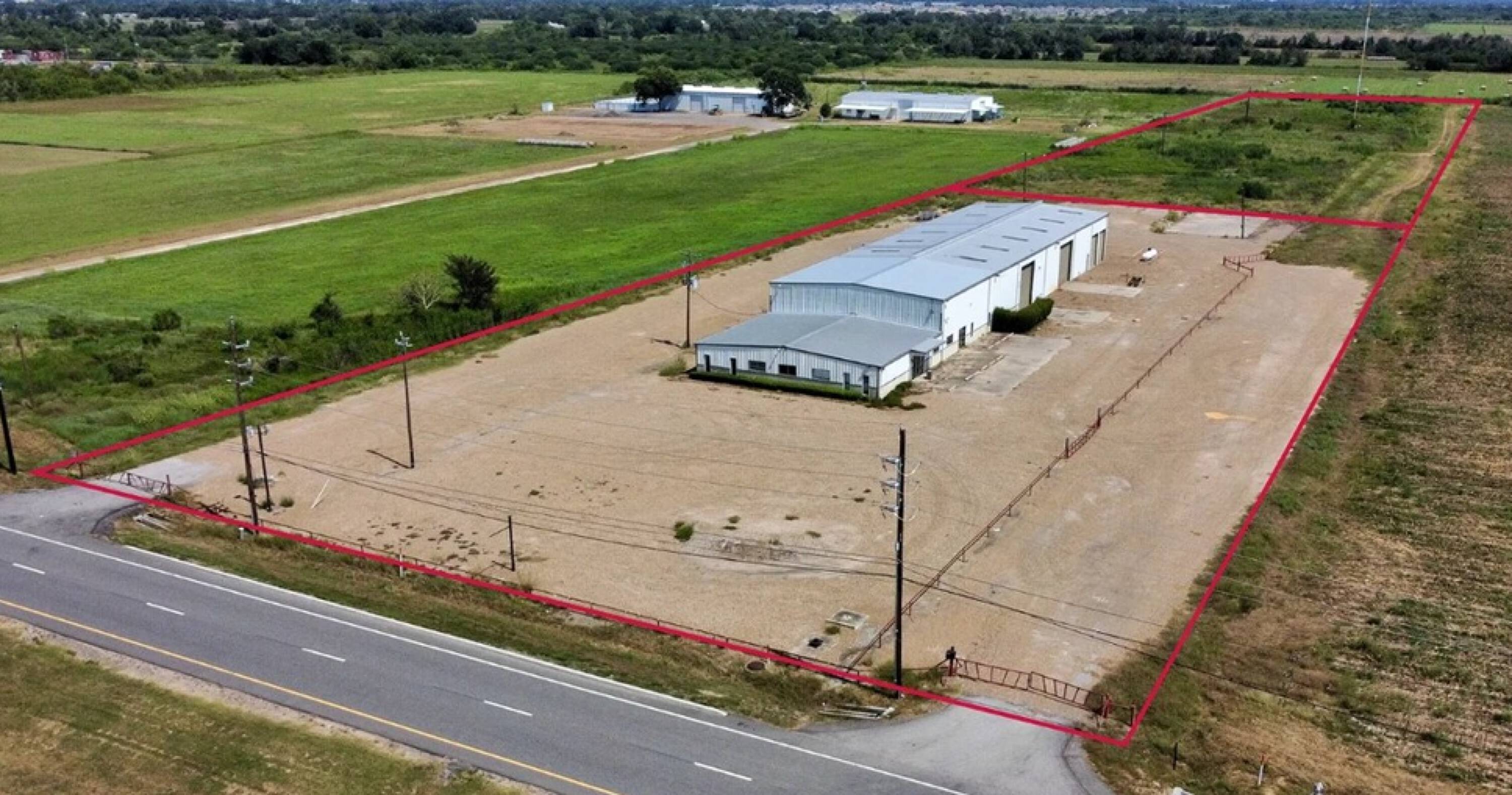 Aerial view of an industrial property with a large warehouse and ample parking on 3.5 stabilized acres in Rosenberg, TX.